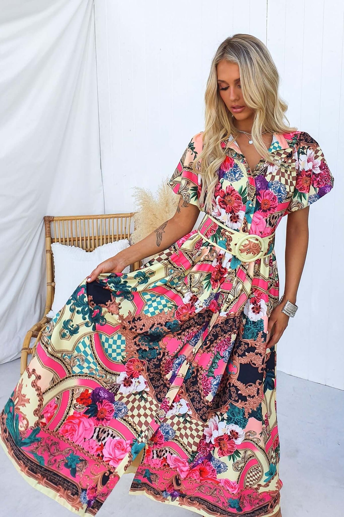 Model wearing the Palermo Maxi Dress with floral patterns, a removable belt, and a button-down front, styled in a bright setting.