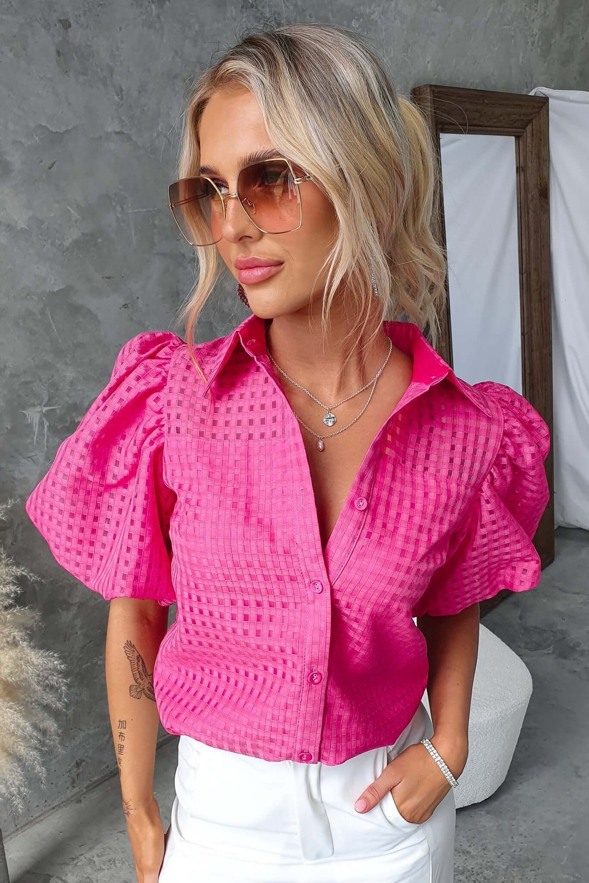 Ursa Shirt in bright pink with puff sleeves, showcasing button-up front and textured fabric against minimalist background.