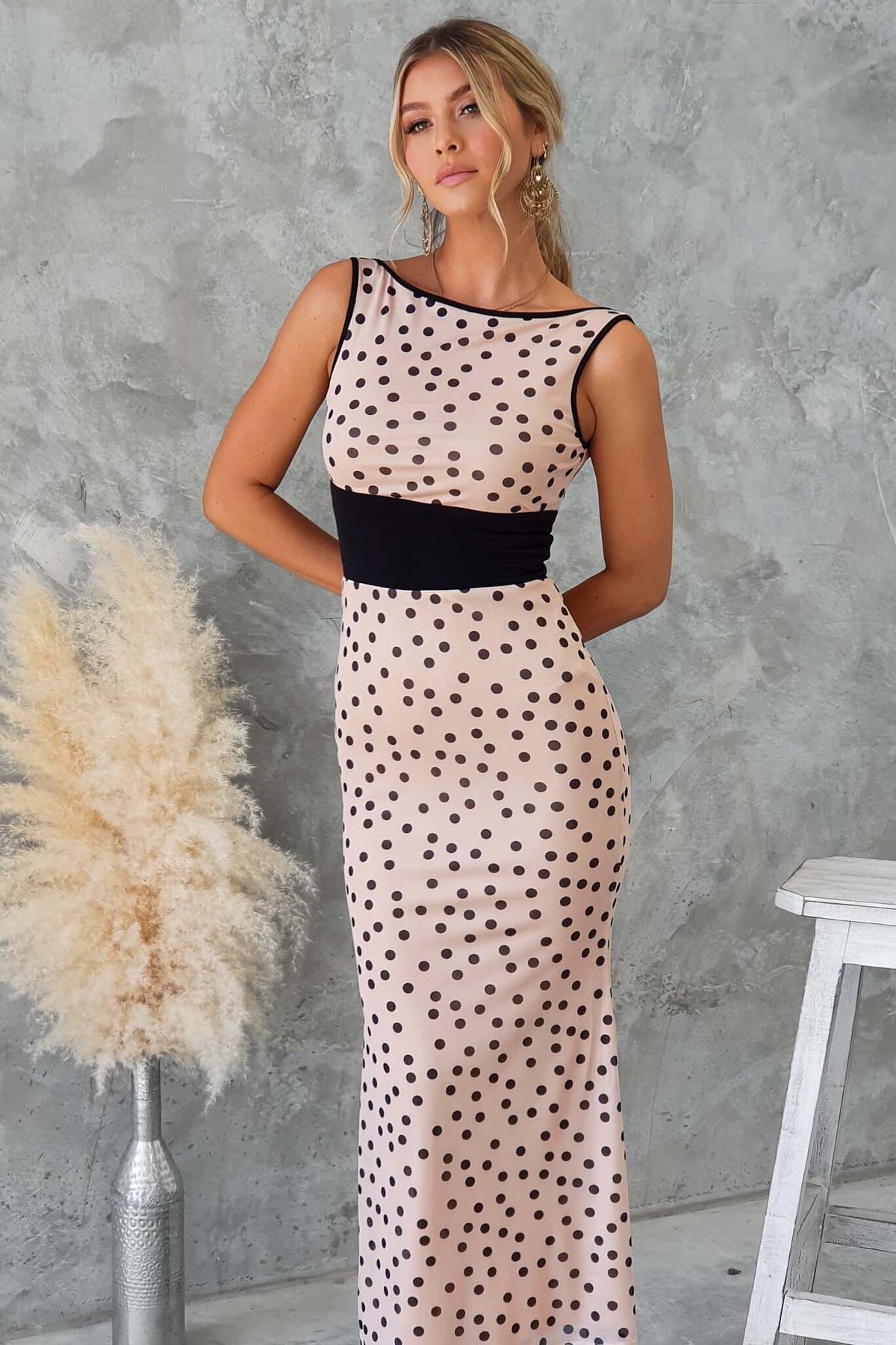 Loreto Maxi Dress with boat neckline, polka dots, and mesh material, showcased against a textured background.