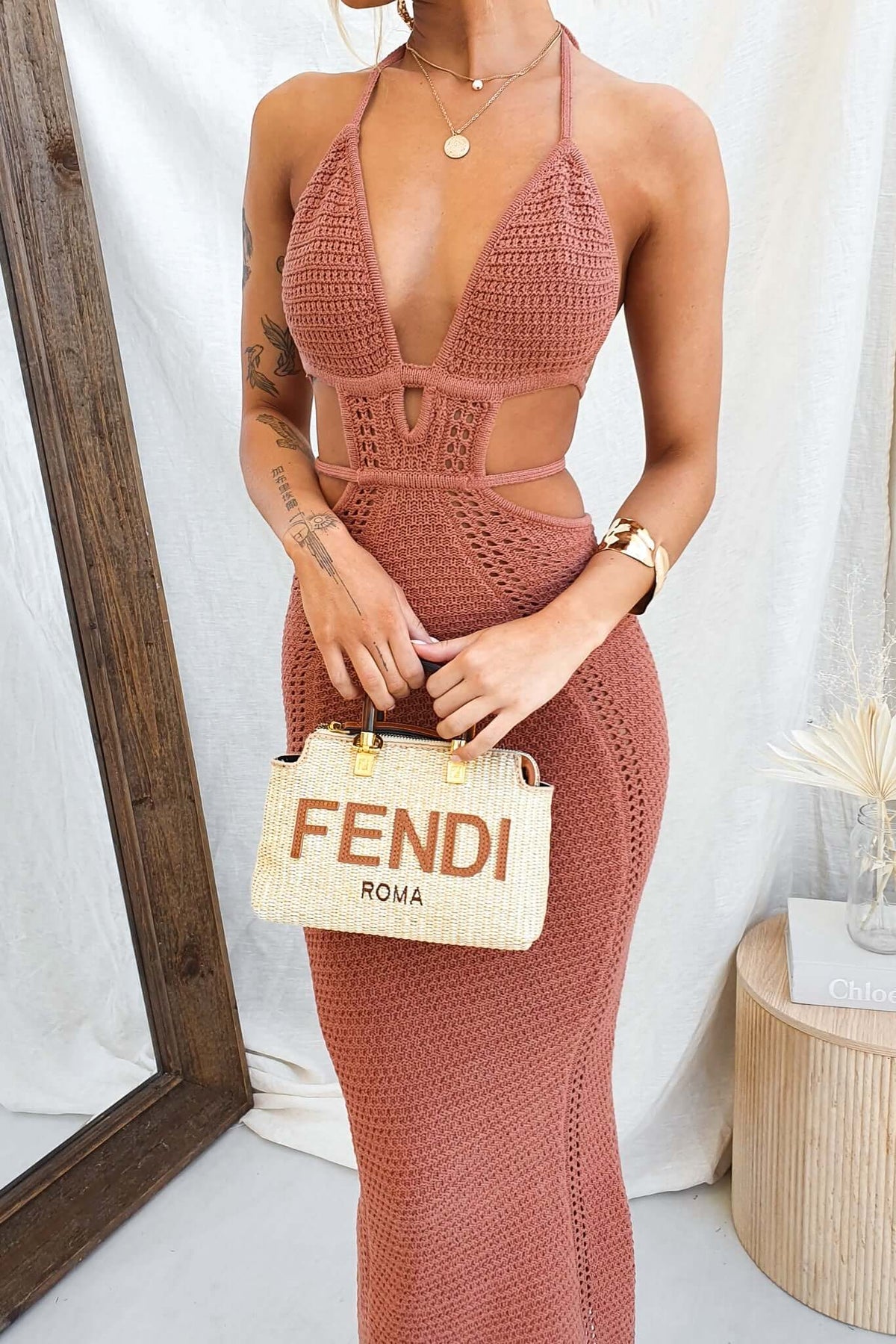 Model wearing the Hold Up Maxi Dress, a crochet gown with adjustable neckline and waist cut-out, paired with a Fendi bag.