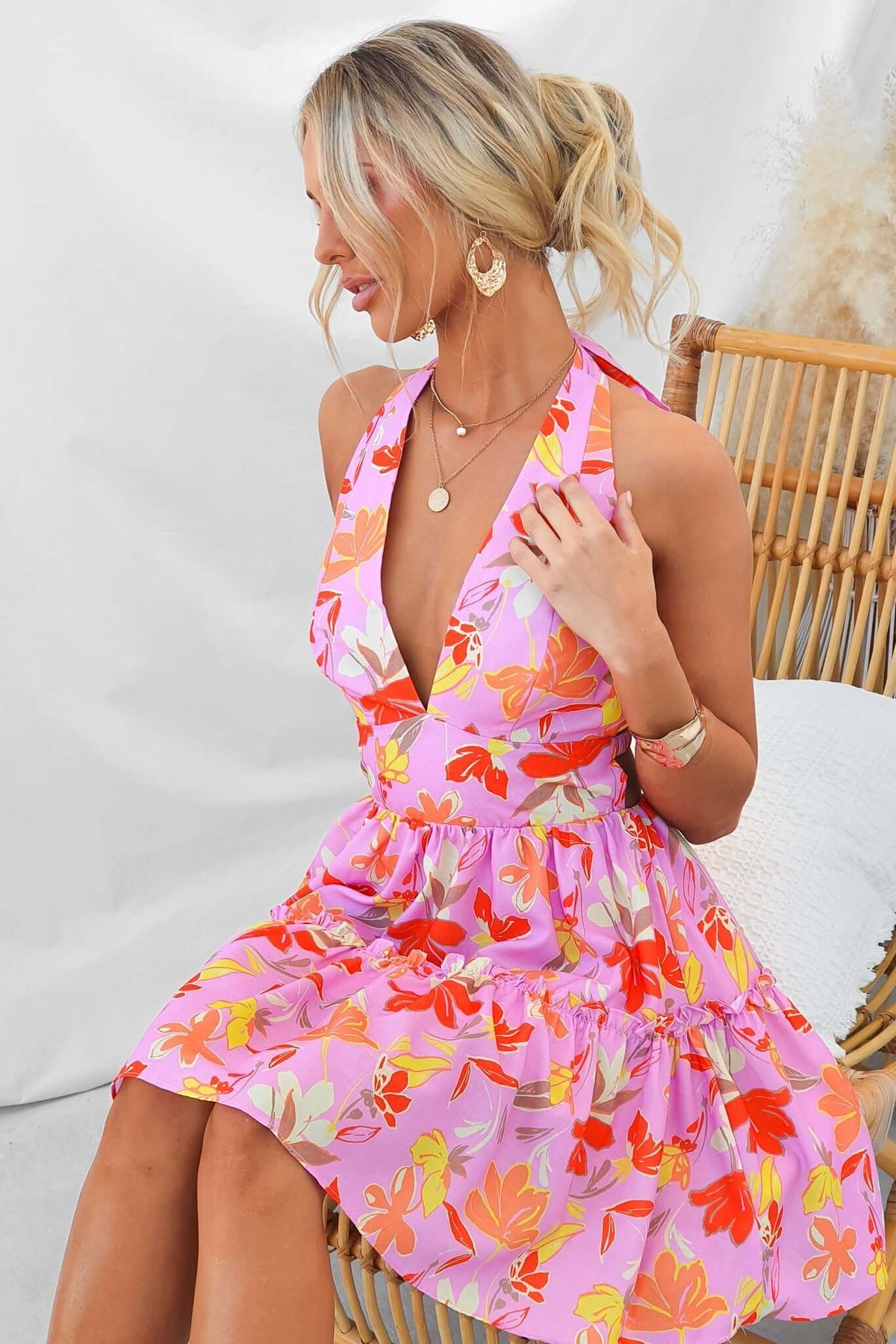 Model wearing a vibrant Buttercup Dress with floral design, featuring a tie neckline and flared skirt.