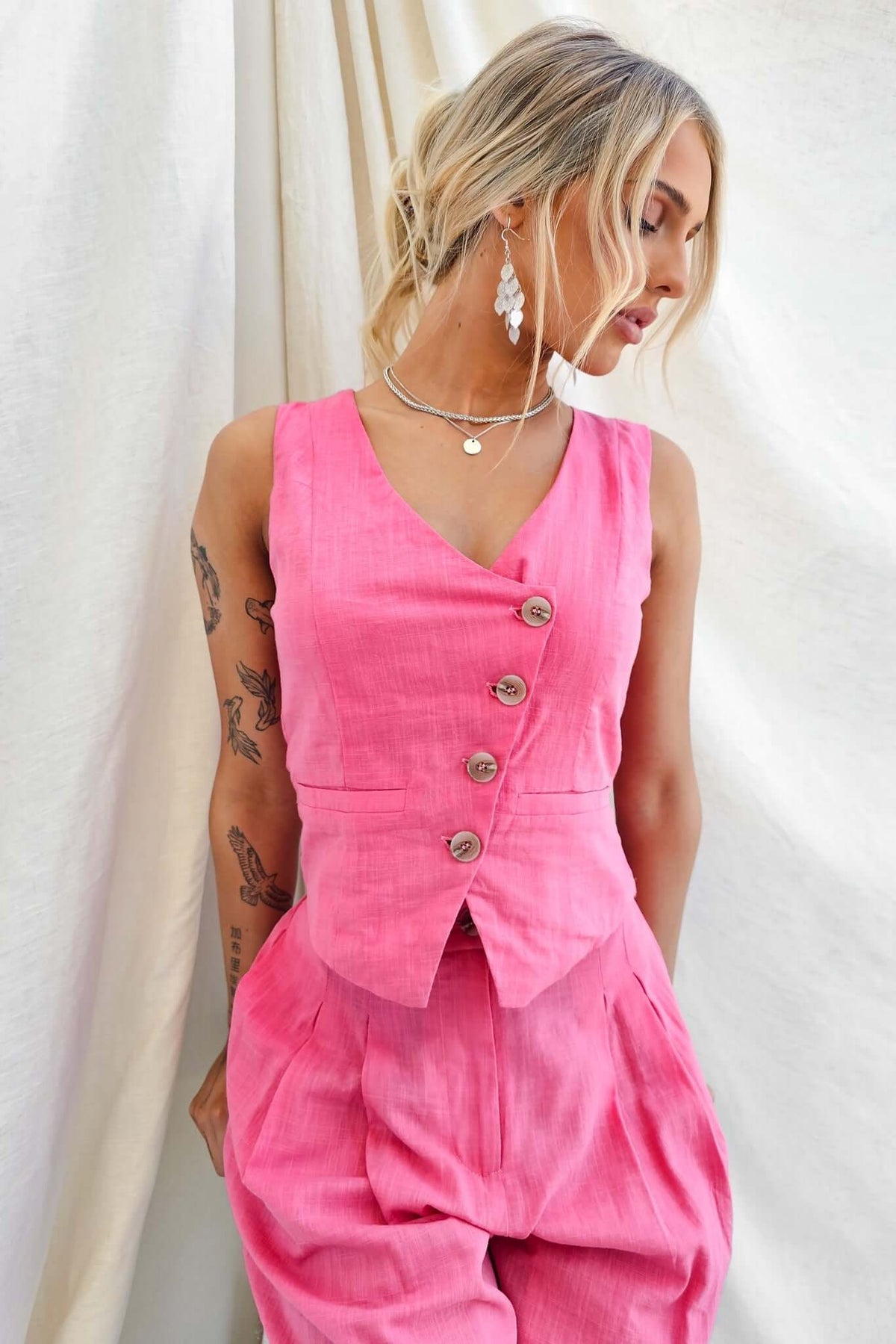 Pink vest top with button-up front, styled with wide-leg pants, perfect for a chic and comfortable outfit.