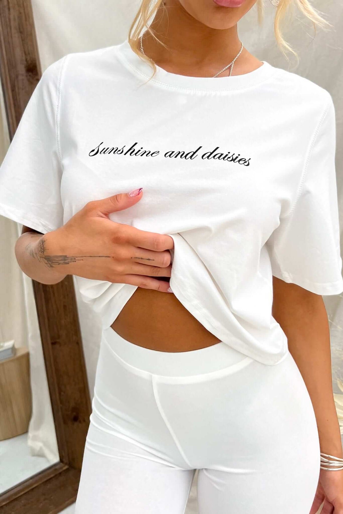 Daisy Tee with 'Sunshine and daisies' print, oversized fit, styled with white leggings.