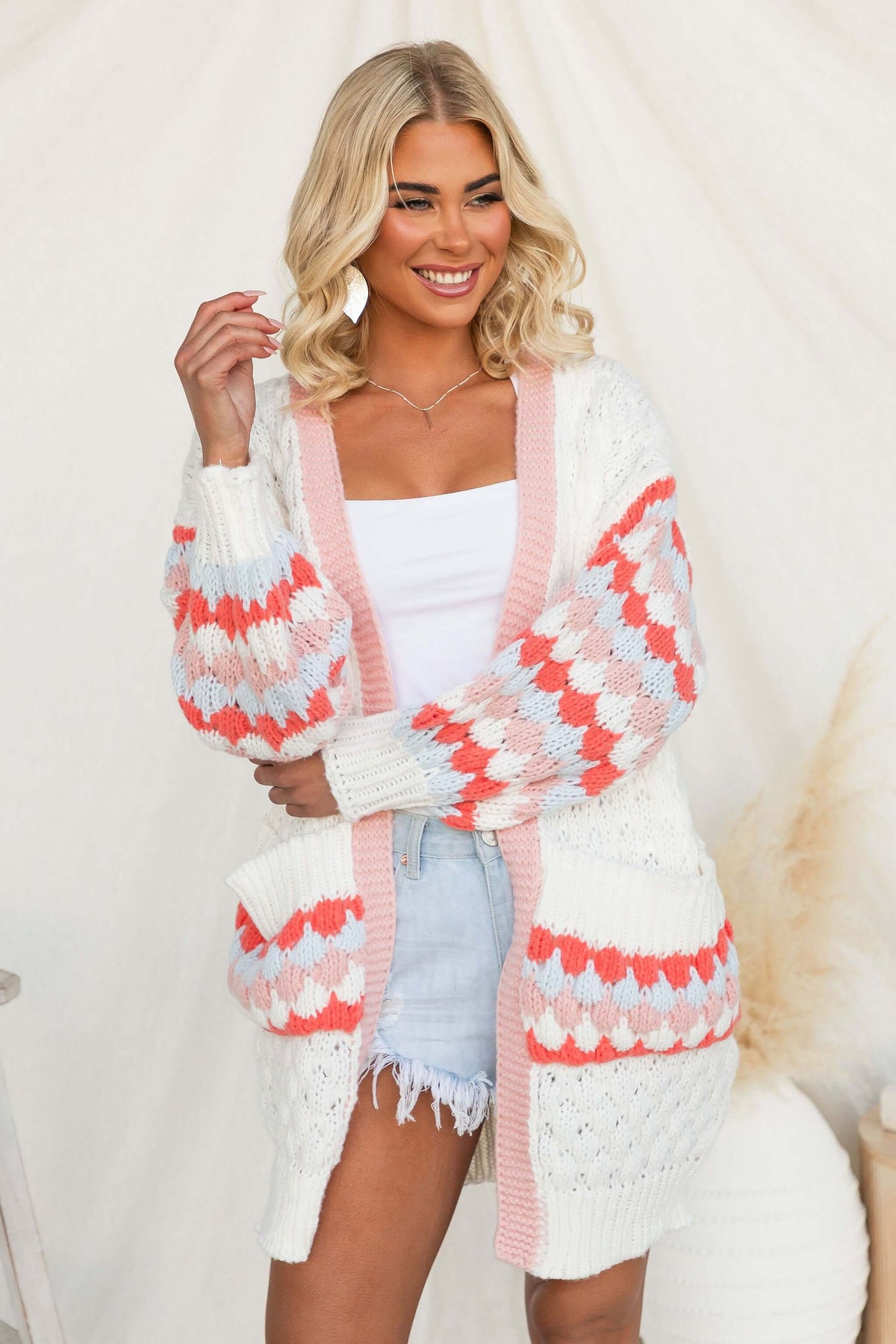 Model wearing a Wild Romance Cardigan with colorful patterns and pockets, styled with shorts and a tank top.