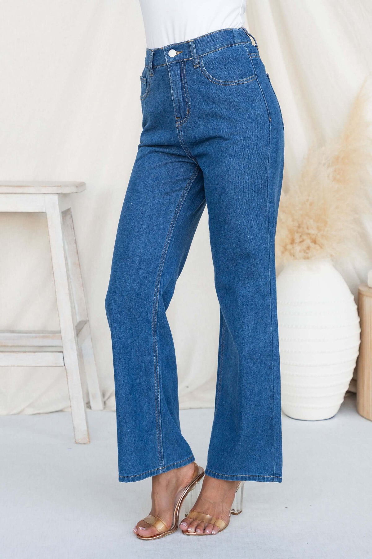 Woman wearing high waist Roman Jeans featuring a zip closure and pockets, styled with heels.
