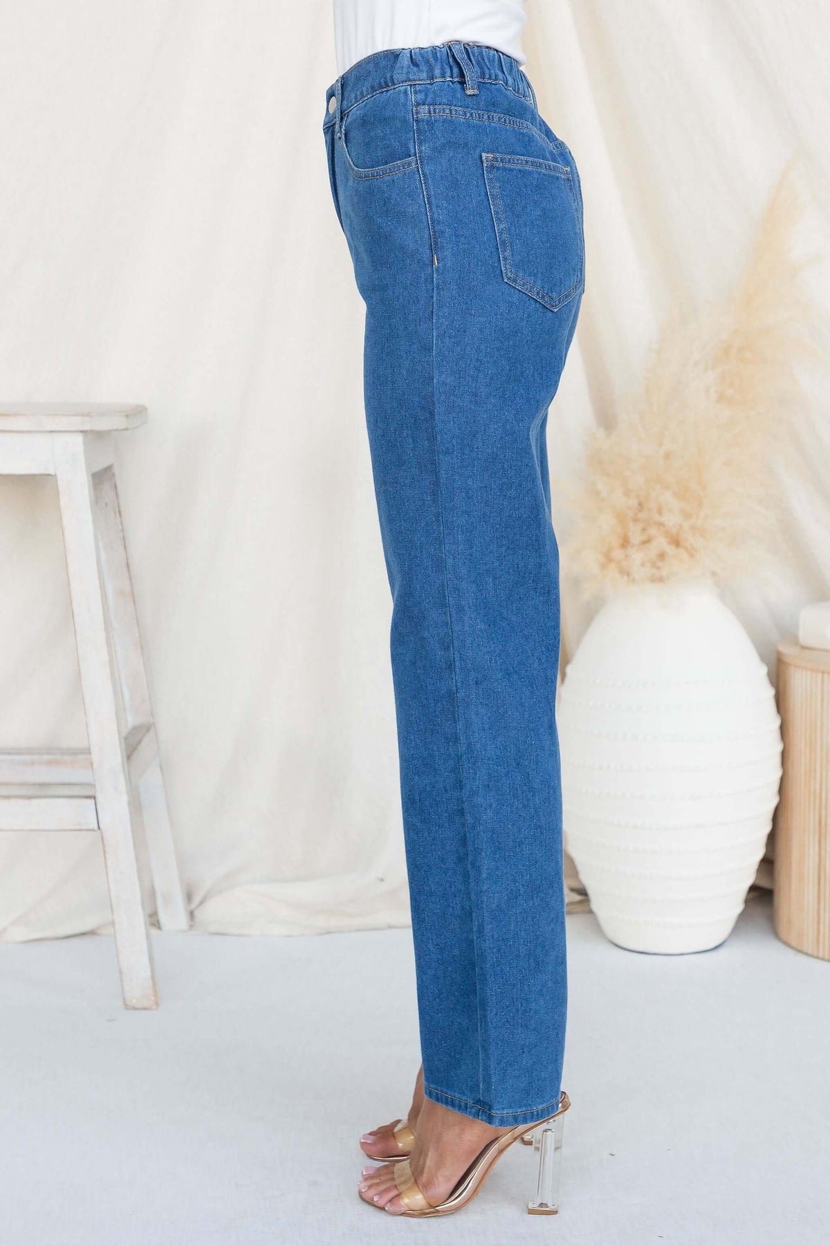 Side view of Roman Jeans featuring high waist fit, elastic back, and classic blue denim with pockets.