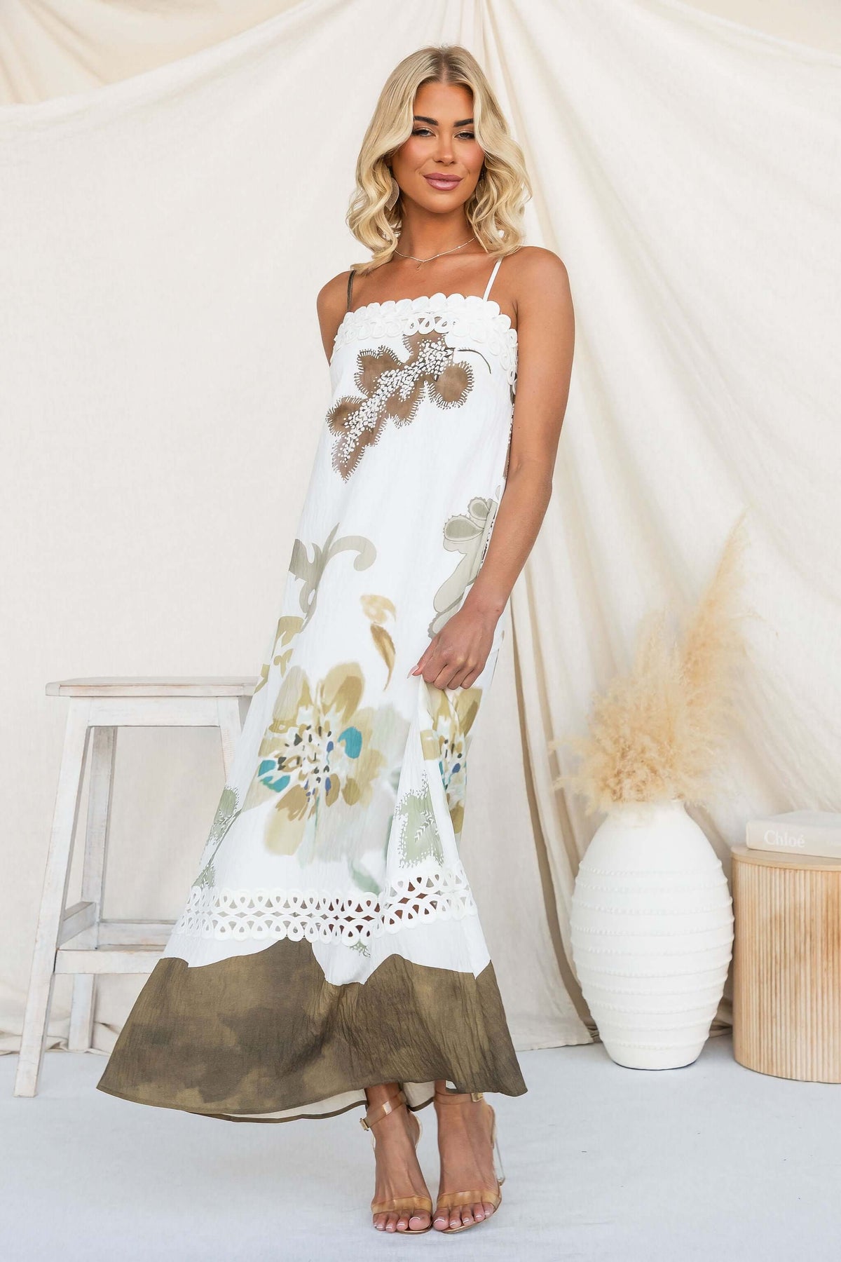 Model wearing Carlo Maxi Dress with floral design and adjustable straps, styled elegantly indoors.