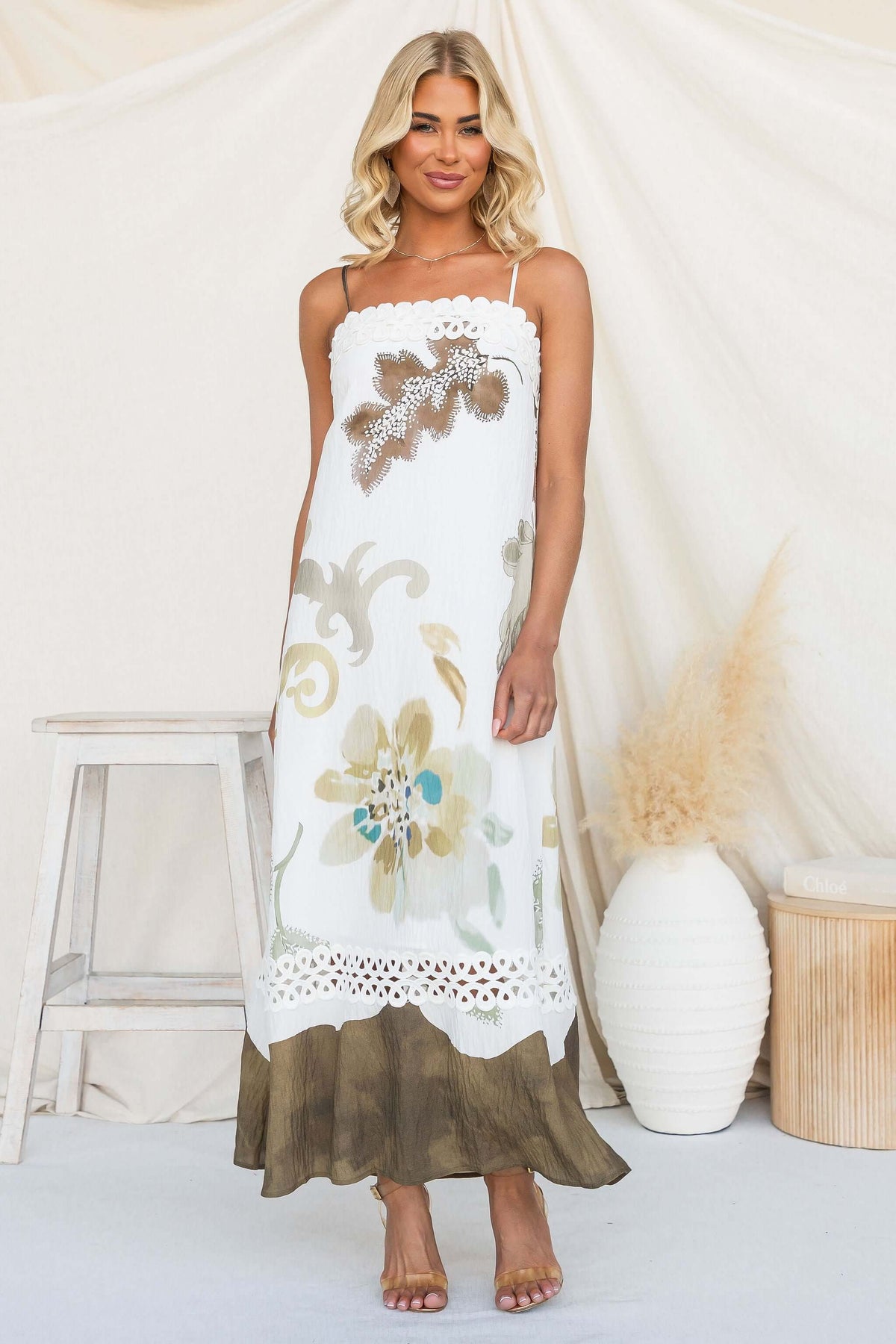 Model wearing Carlo Maxi Dress with floral design and adjustable straps, showcased in natural setting.