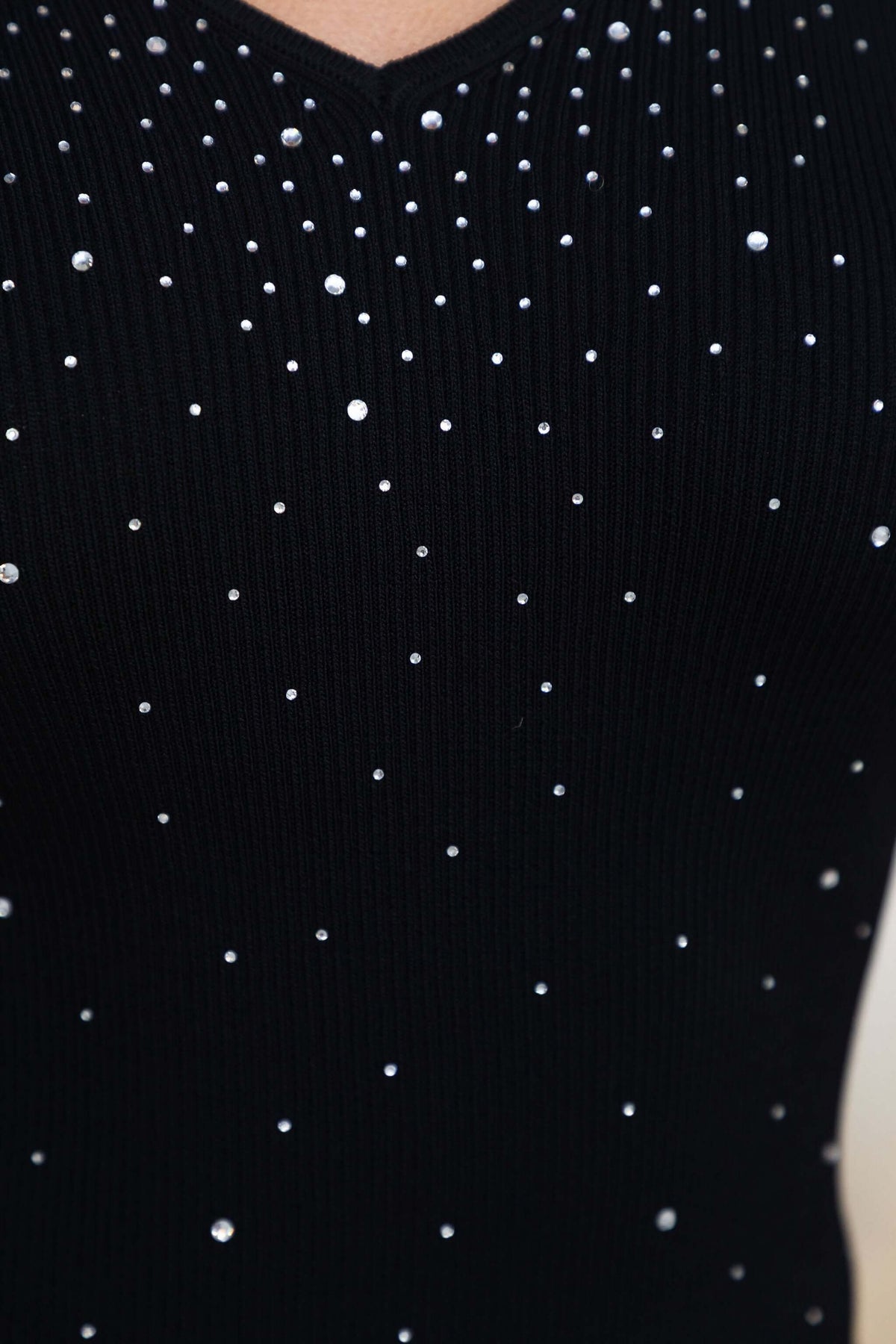Close-up of the knitted Marianne Top featuring diamantes on a black V-neckline fabric.