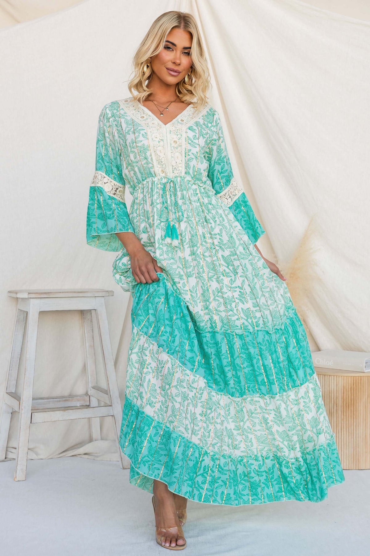 Model wearing Mystic Maxi Dress featuring a V-neckline, elastic waistband, and floral metallic print.