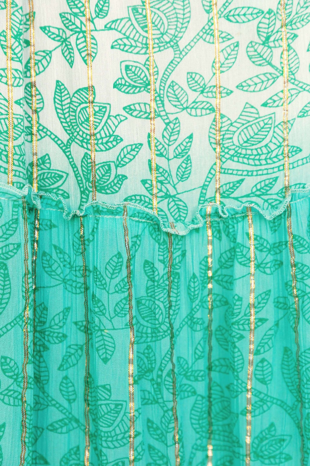 Close-up of the Mystic Maxi Dress fabric featuring green leaf patterns and metallic gold accents.