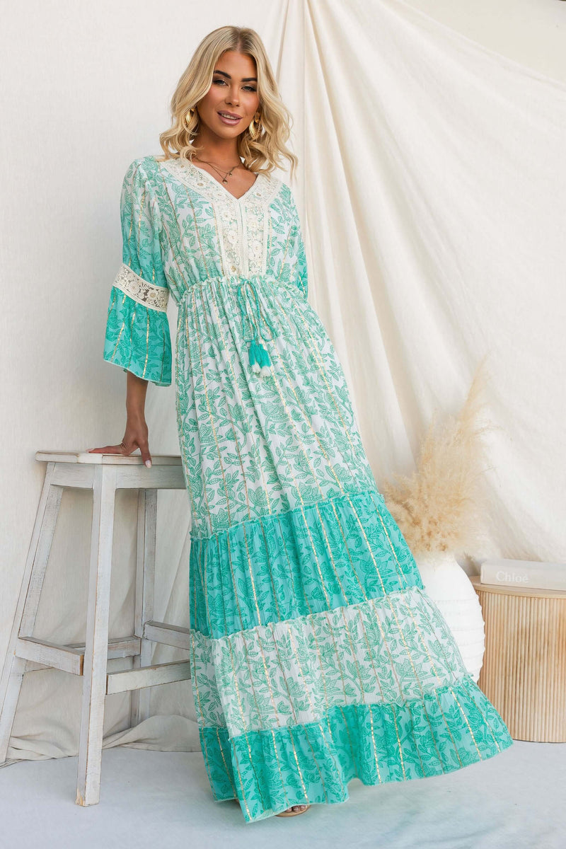 Model wearing a Mystic Maxi Dress with V-neckline and metallic print, featuring an elastic waistband and pockets.