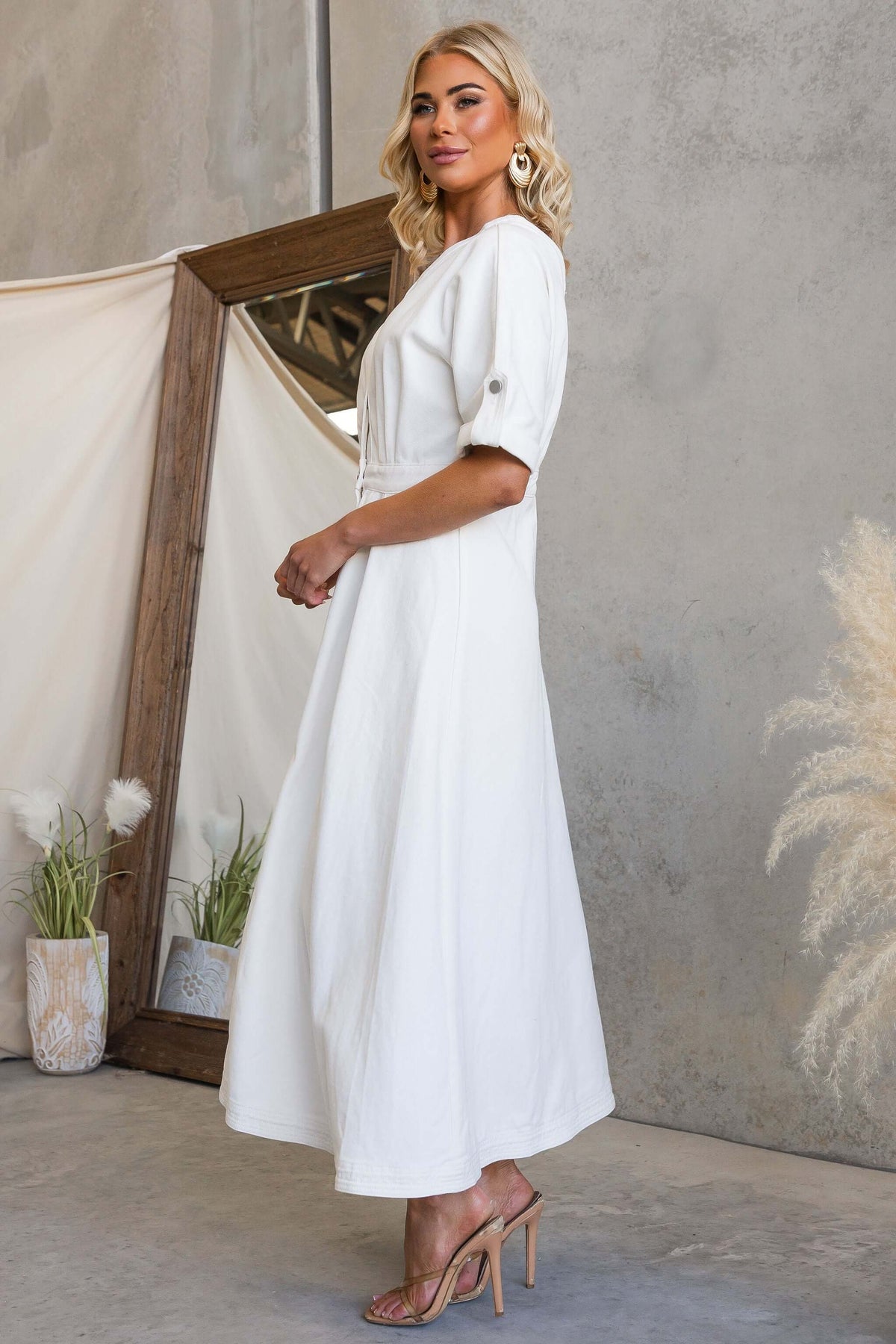 Model wearing Saddle Bloom Denim Midi Dress featuring a v-neckline and button details in a stylish interior.