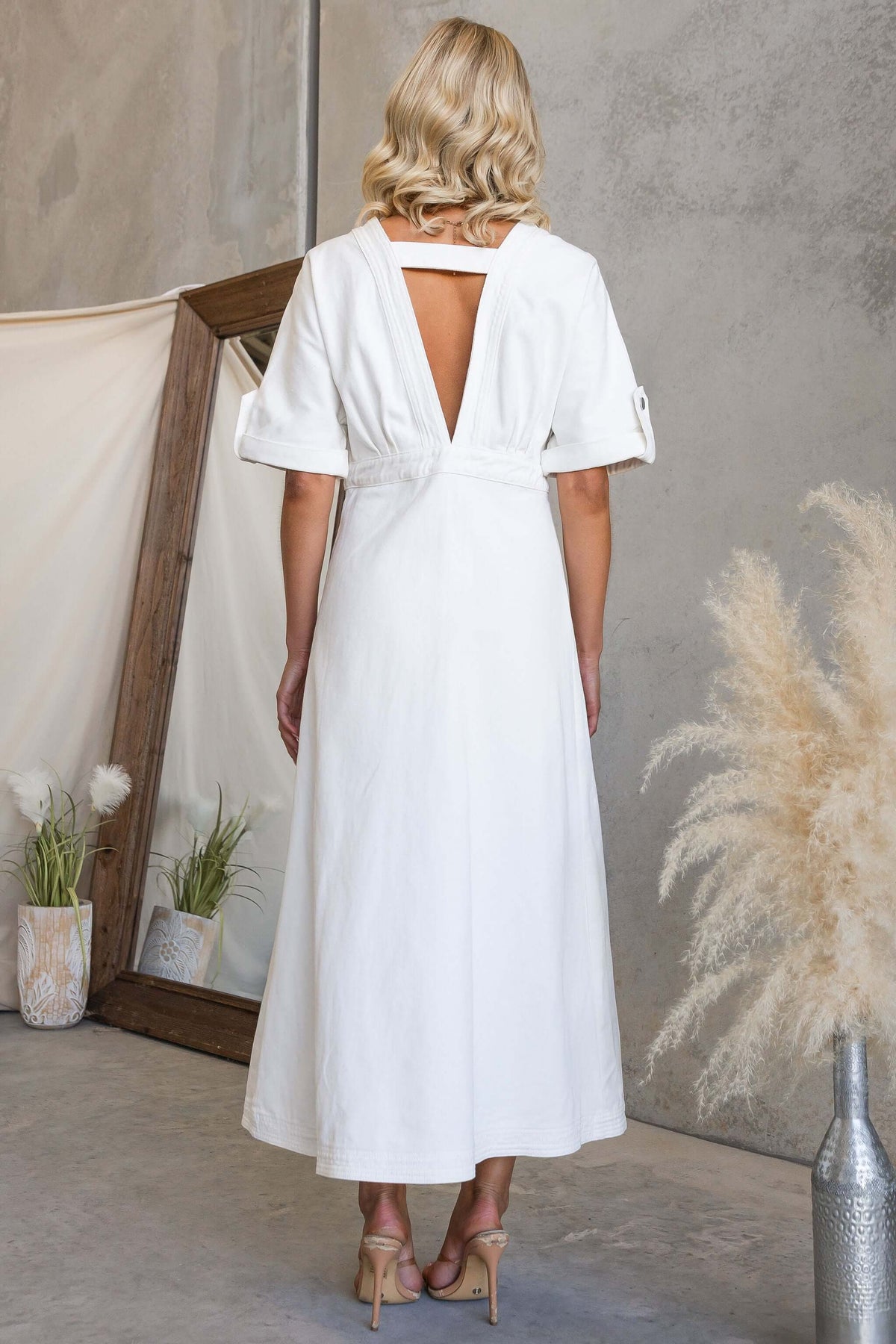 Back view of a woman wearing a white dress showcasing the Saddle Bloom Denim Midi Dress design.