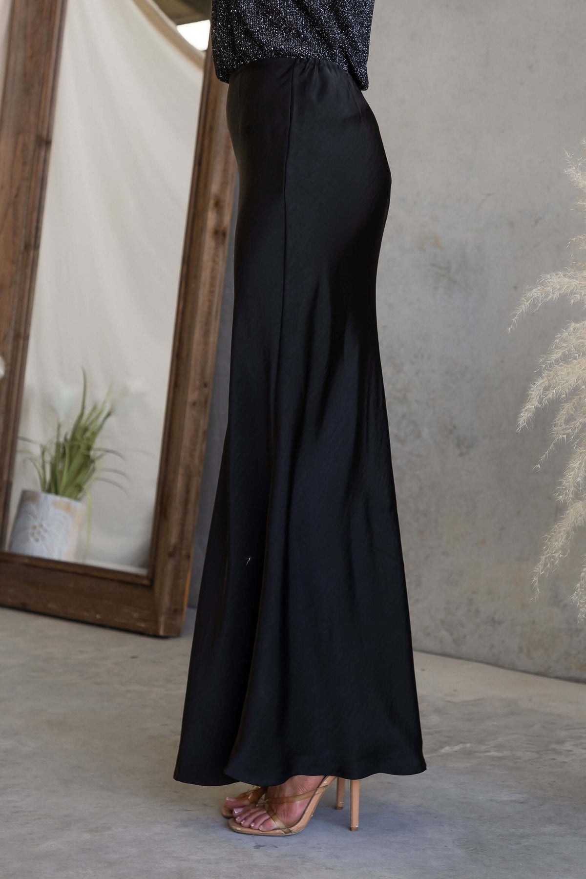 Side view of the Moonlit Muse Maxi Skirt in black, featuring a mid-high waist fit and elegant flow.