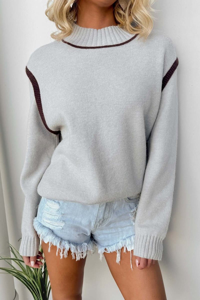 Stylish model wearing Nights Out Jumper with mock neckline and knit material, paired with denim shorts.