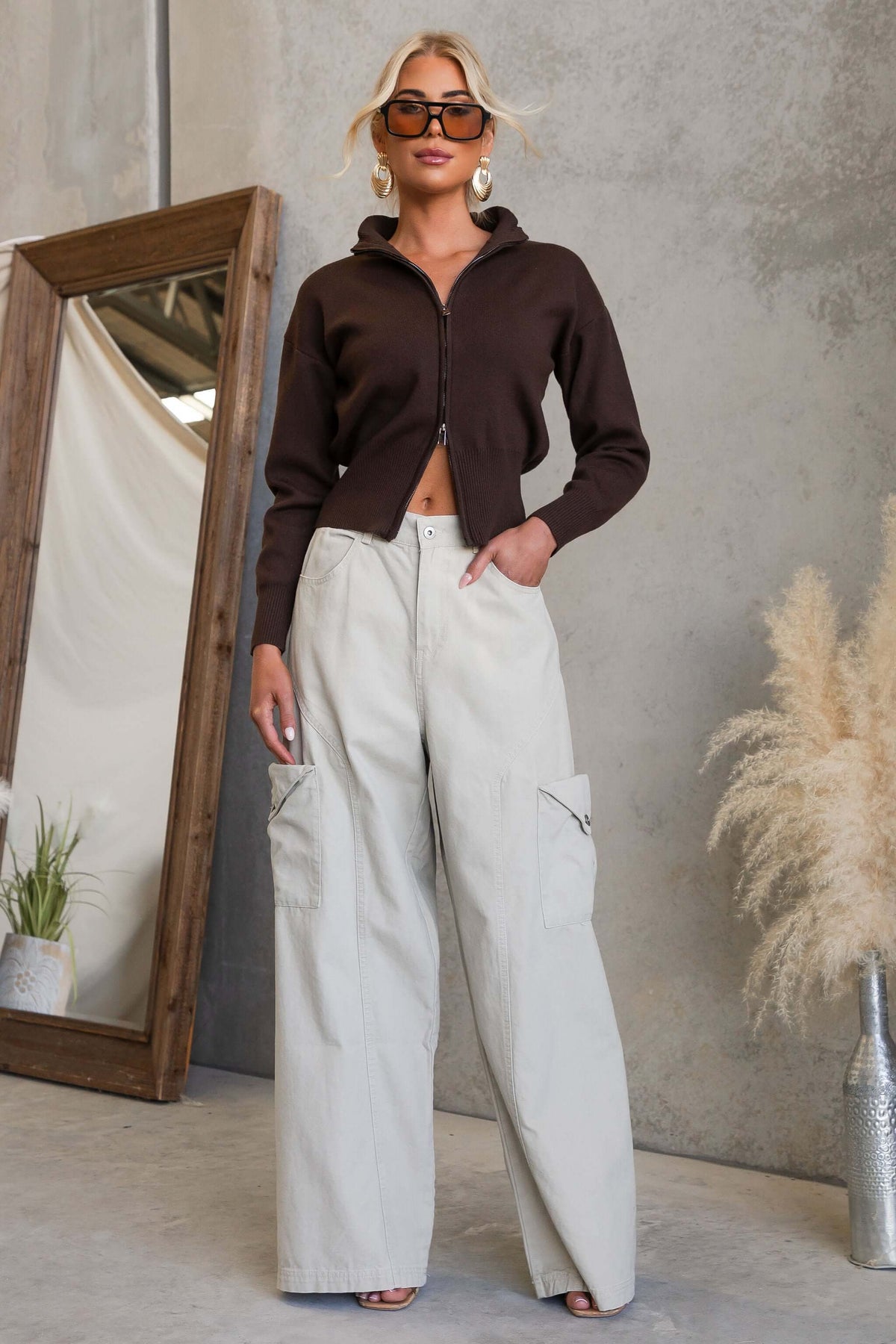 Model wearing Rebel Cargo Jeans styled with a brown zip-up top in a chic indoor setting.