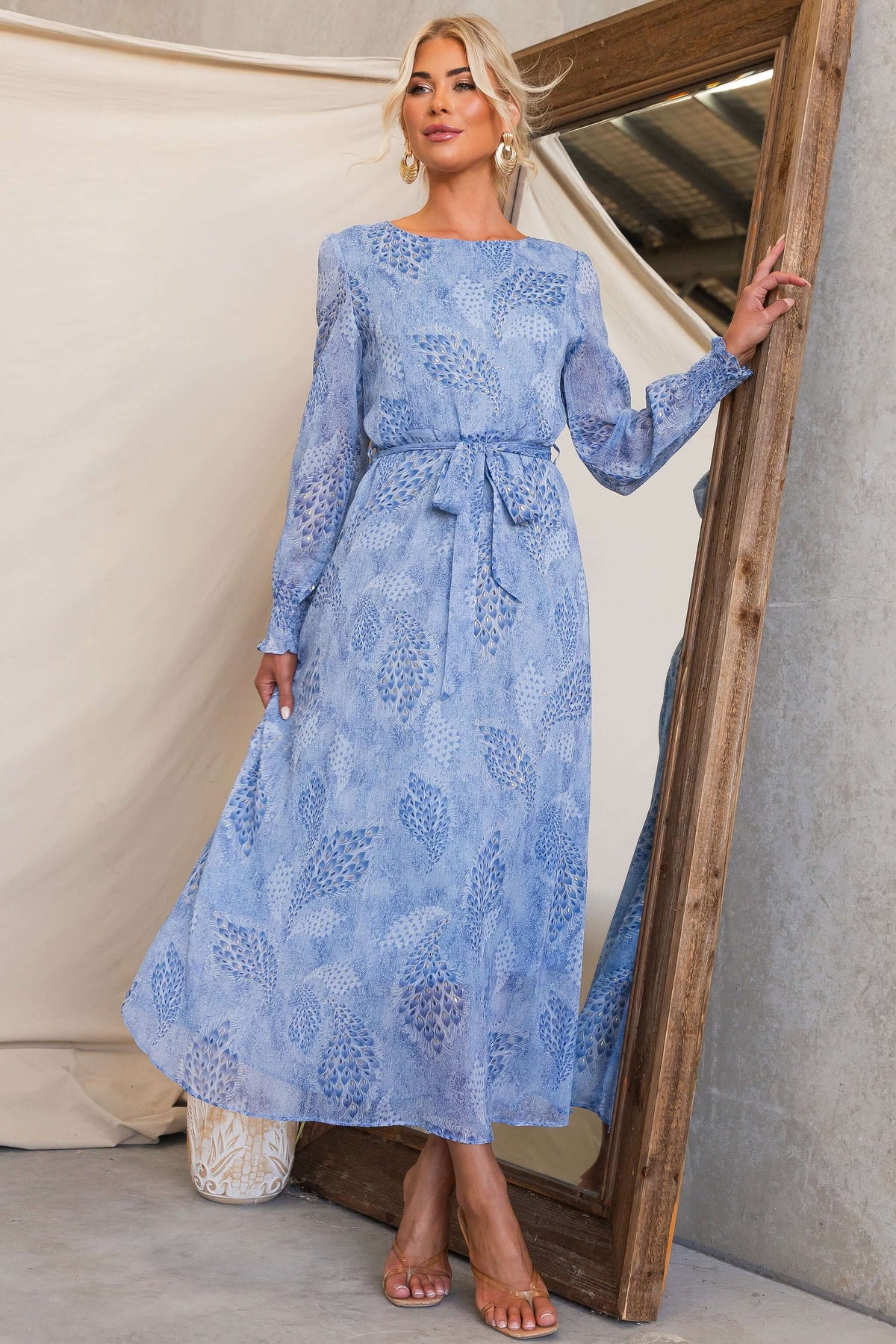 Model wearing the Morning Light Maxi Dress with a blue floral pattern, featuring a removable tie and elegant sleeves.