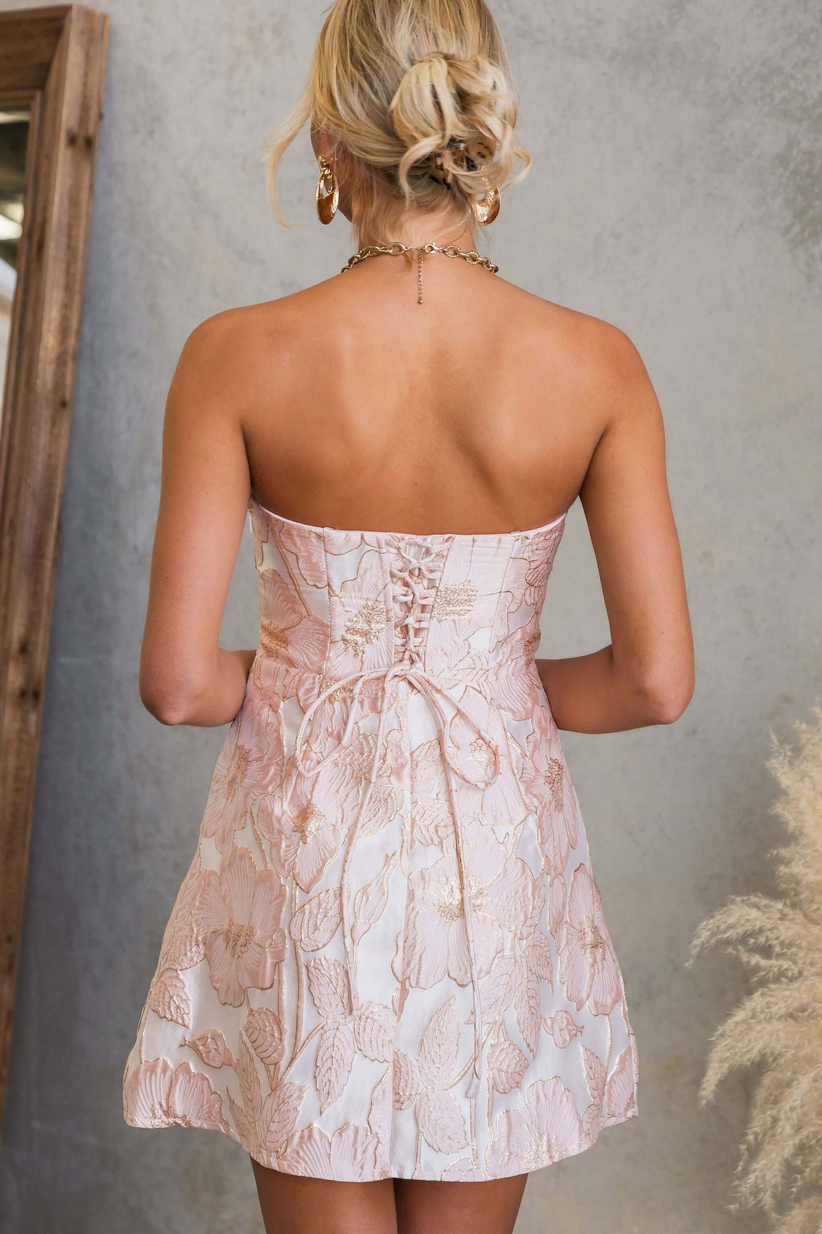 Back view of the Matilda Dress showcasing its lace-up style and textured metallic fabric.