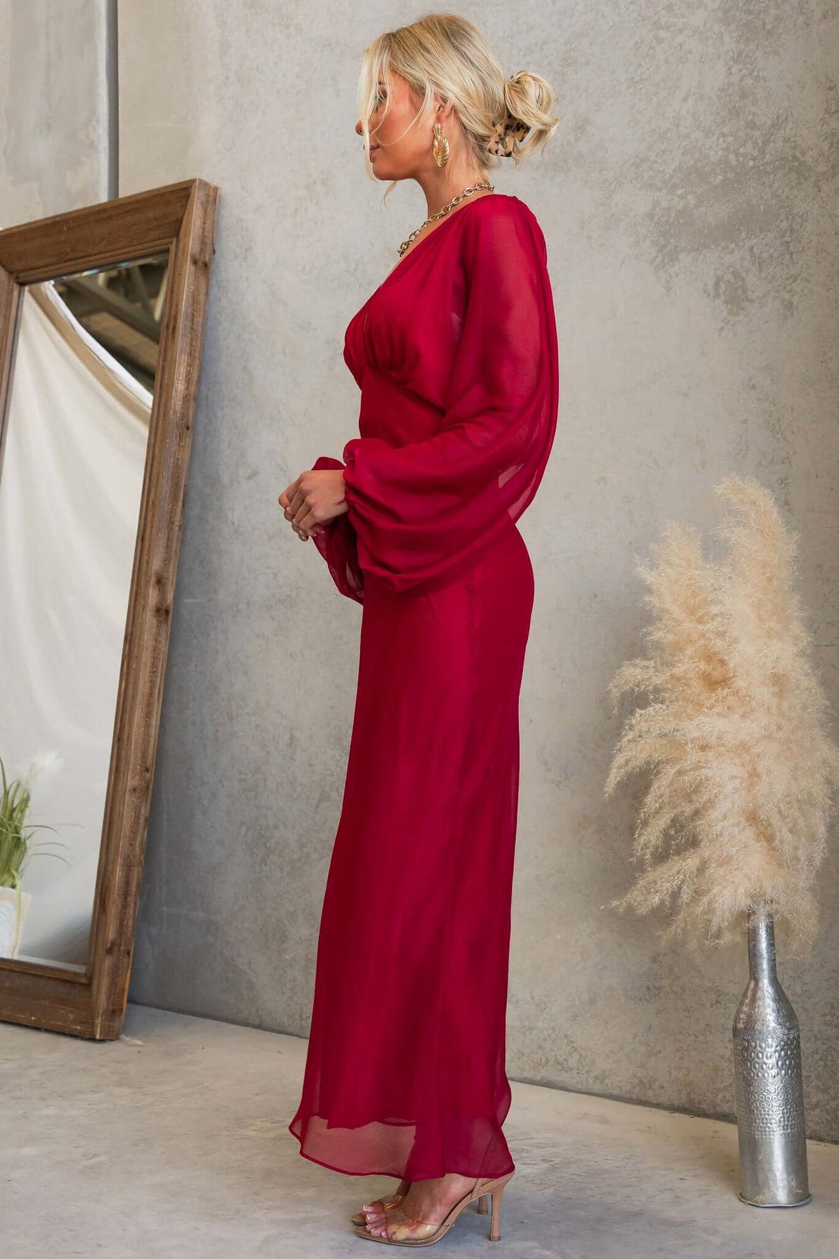 Model wearing the elegant Nightfall Maxi Dress in red chiffon, showcasing the V-neckline and elastic cuffs.