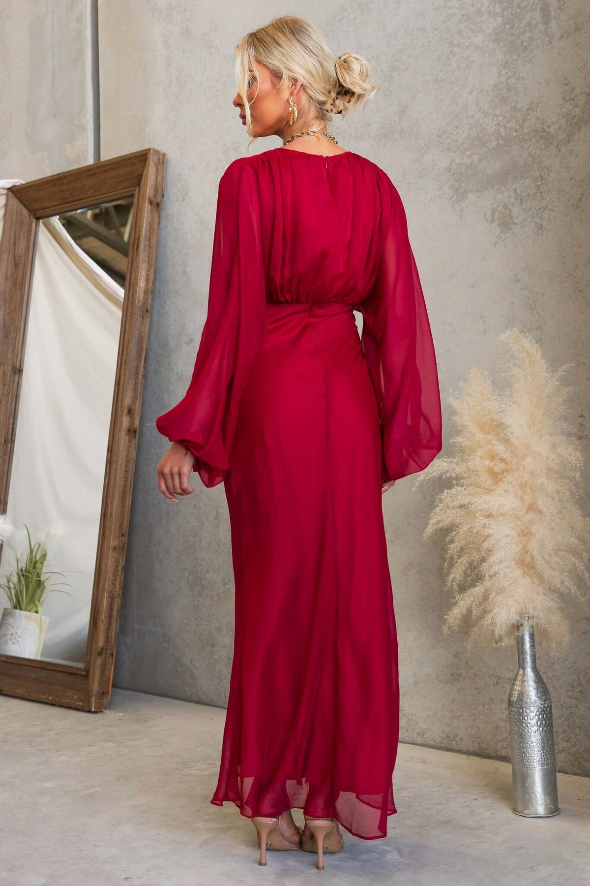 Back view of a model in a red Nightfall Maxi Dress with chiffon material and elastic cuffs.