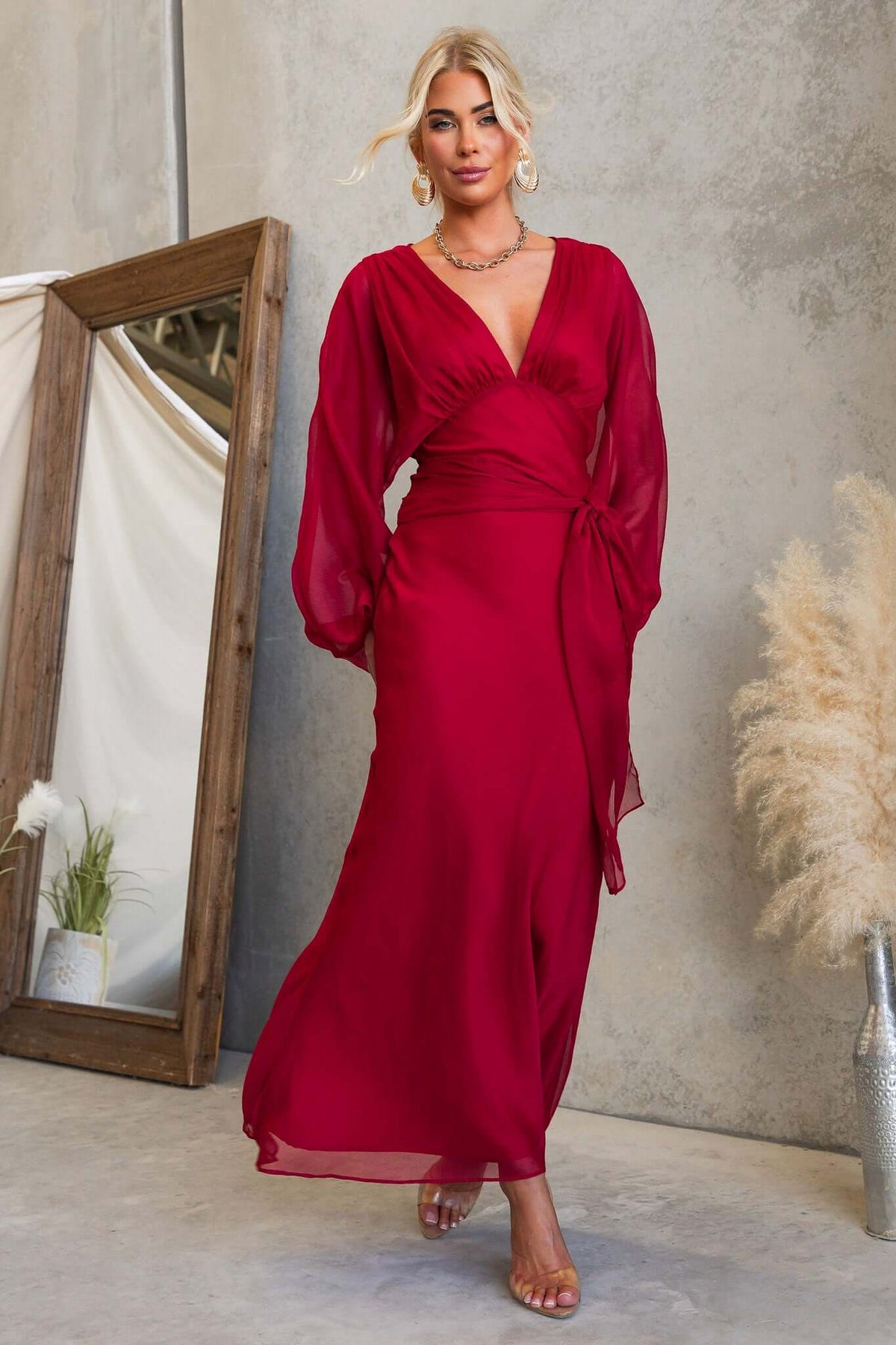 Model showcasing a stylish Nightfall Maxi Dress in red with a V-neckline and chiffon material.
