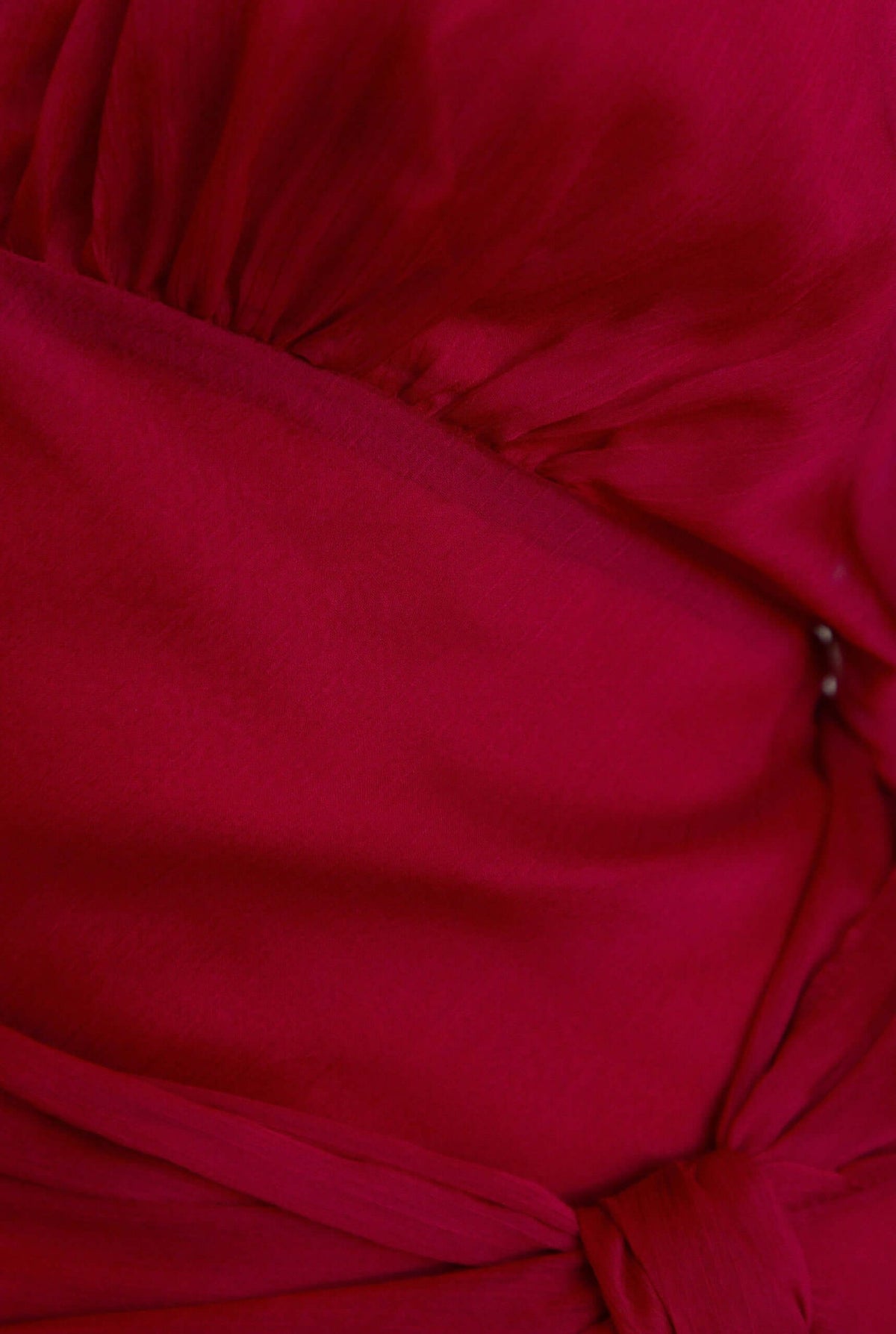 Close-up of the fabric detail and tie of the Nightfall Maxi Dress in rich red chiffon material.