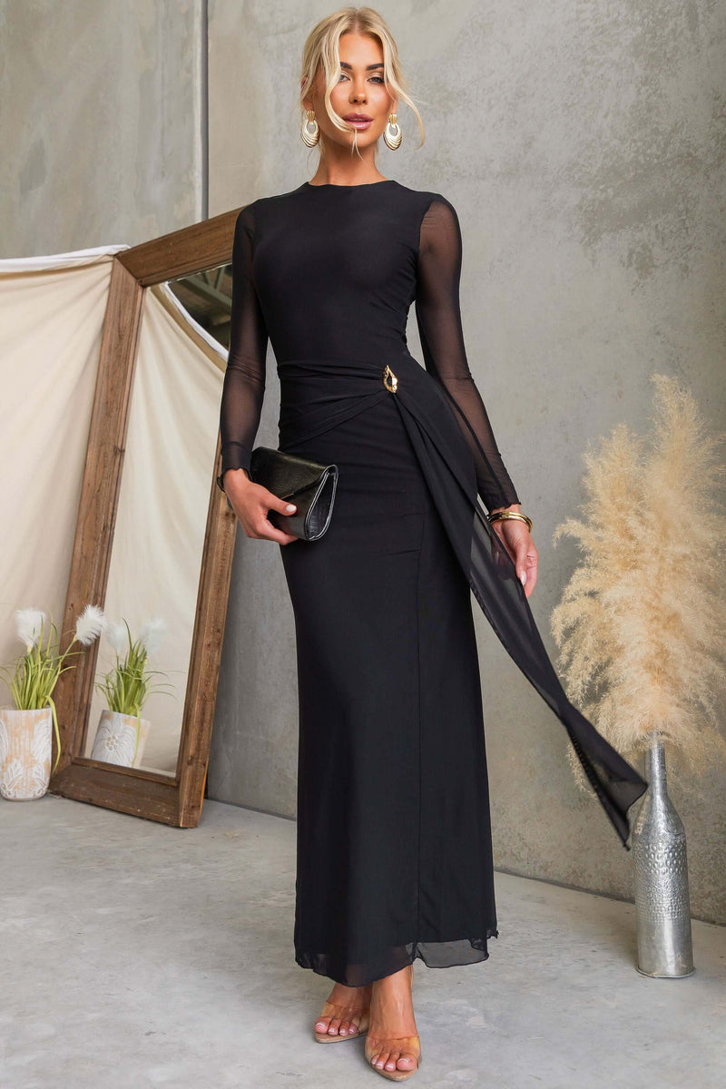 Model wearing La Rose Maxi Dress, featuring black draping material, round neckline, and chic gold hardware.