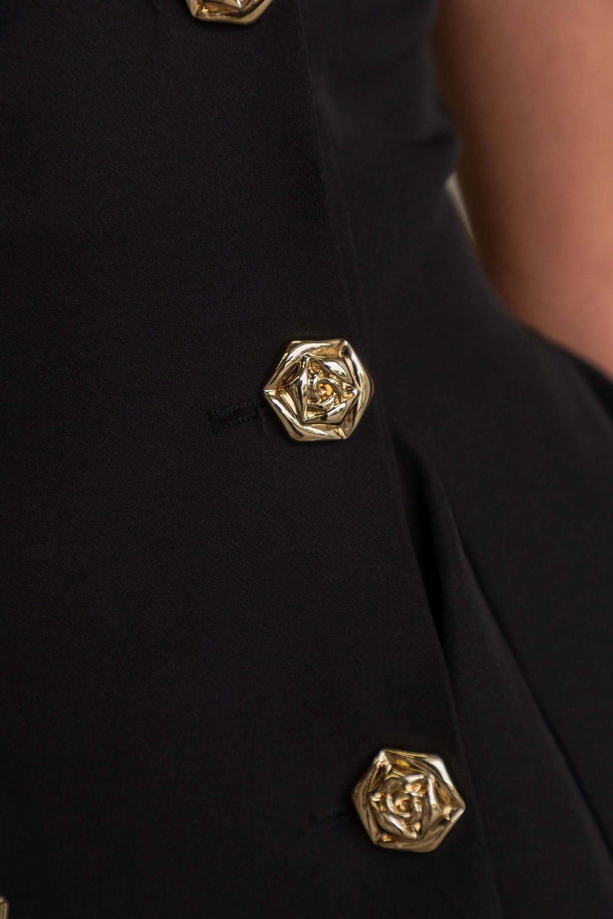 Close-up of the elegant buttons on The Signature Dress, showcasing luxurious gold detailing on a black fabric.