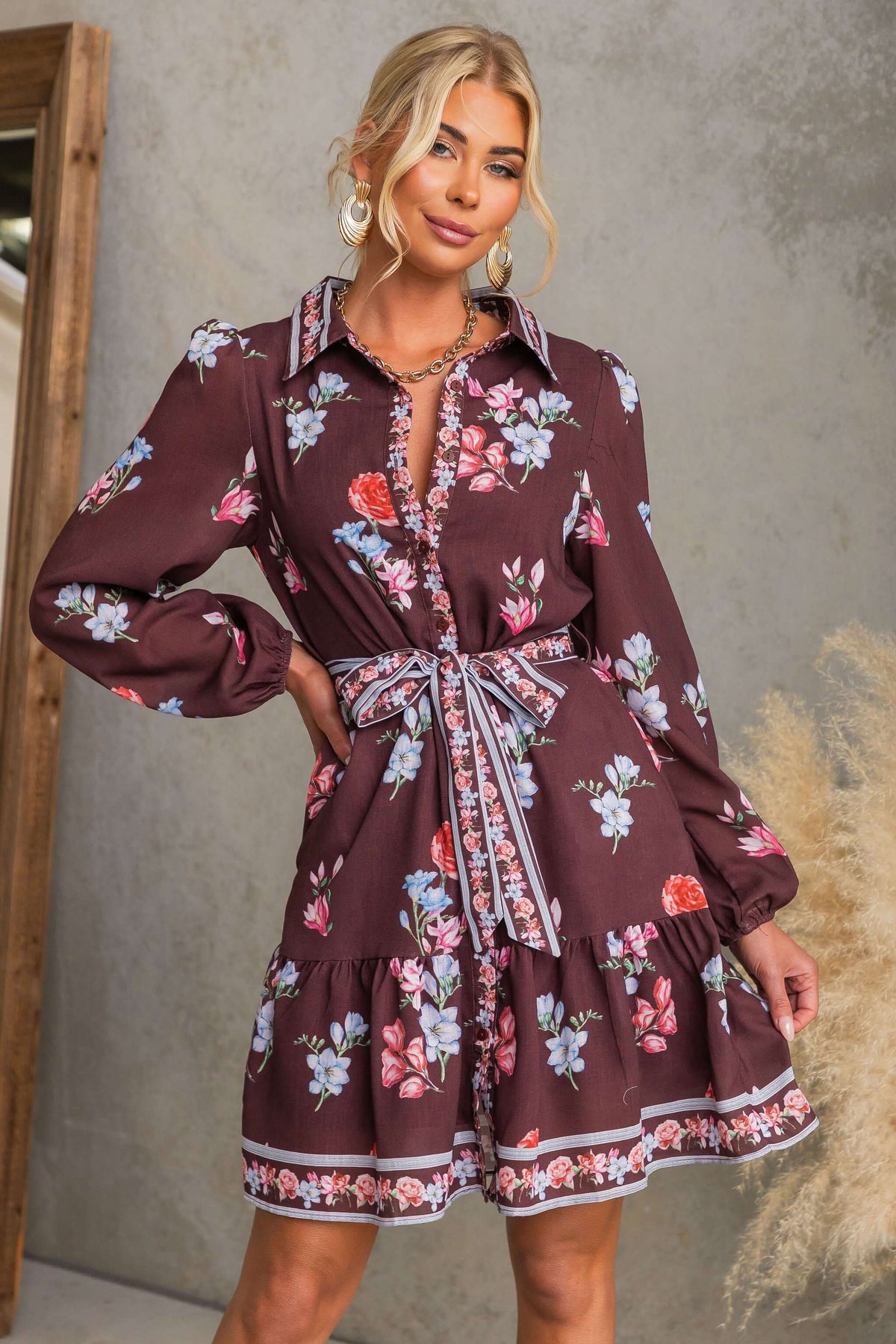 Model wearing Fergy Dress featuring floral patterns, button-up front, and removable tie.