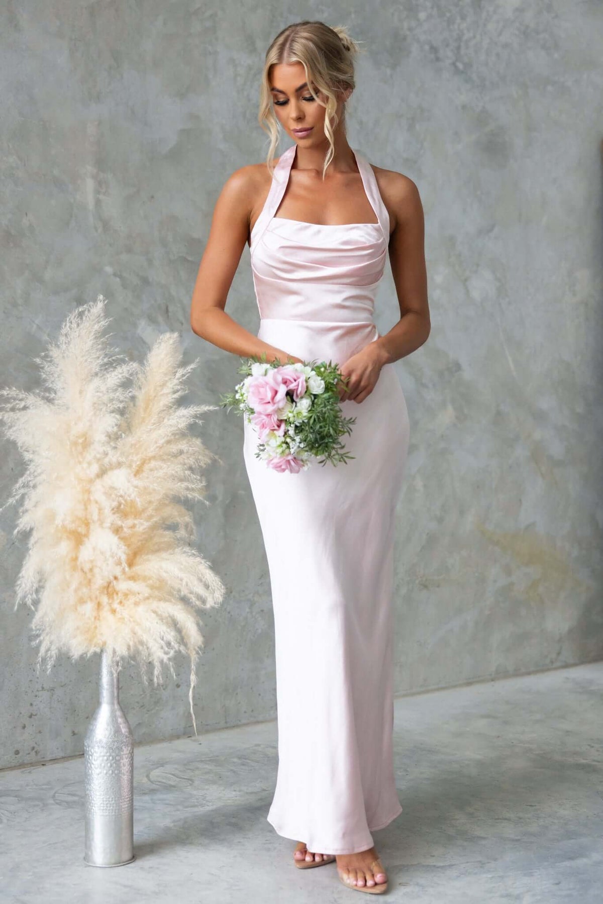 Abigail Maxi Dress in soft satin with halter neckline; model holding flowers, elegant bridal style, perfect for special occasions.