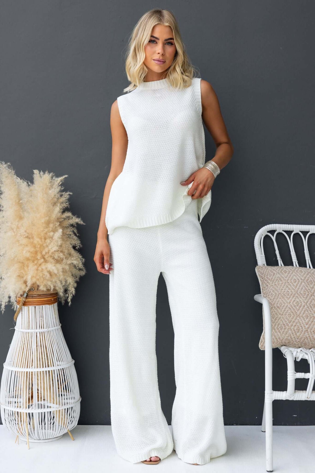 Model wearing Aera Top with high neckline and open back, styled with matching pants, showcasing knit material and relaxed fit.