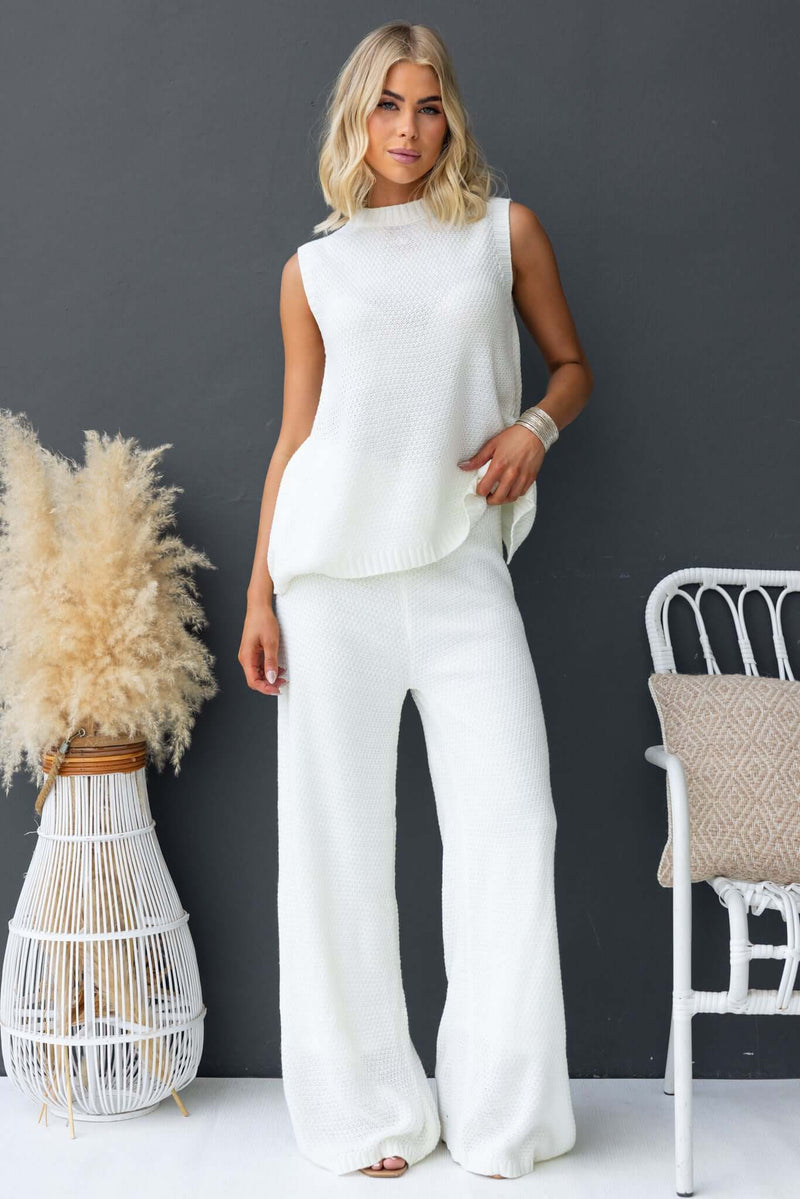 Model wearing Aera Top with high neckline and open back, styled with matching pants, showcasing knit material and relaxed fit.
