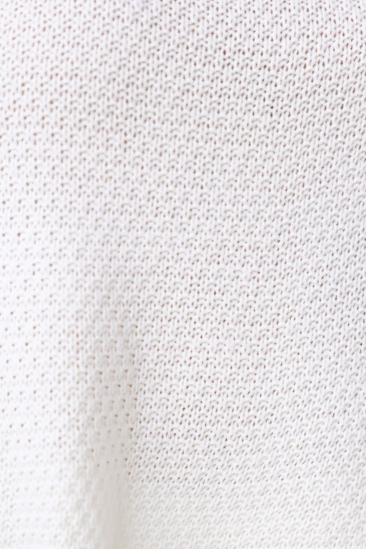 Close-up texture of Aera Top in white knit material, showcasing its breathable and stretchy fabric.