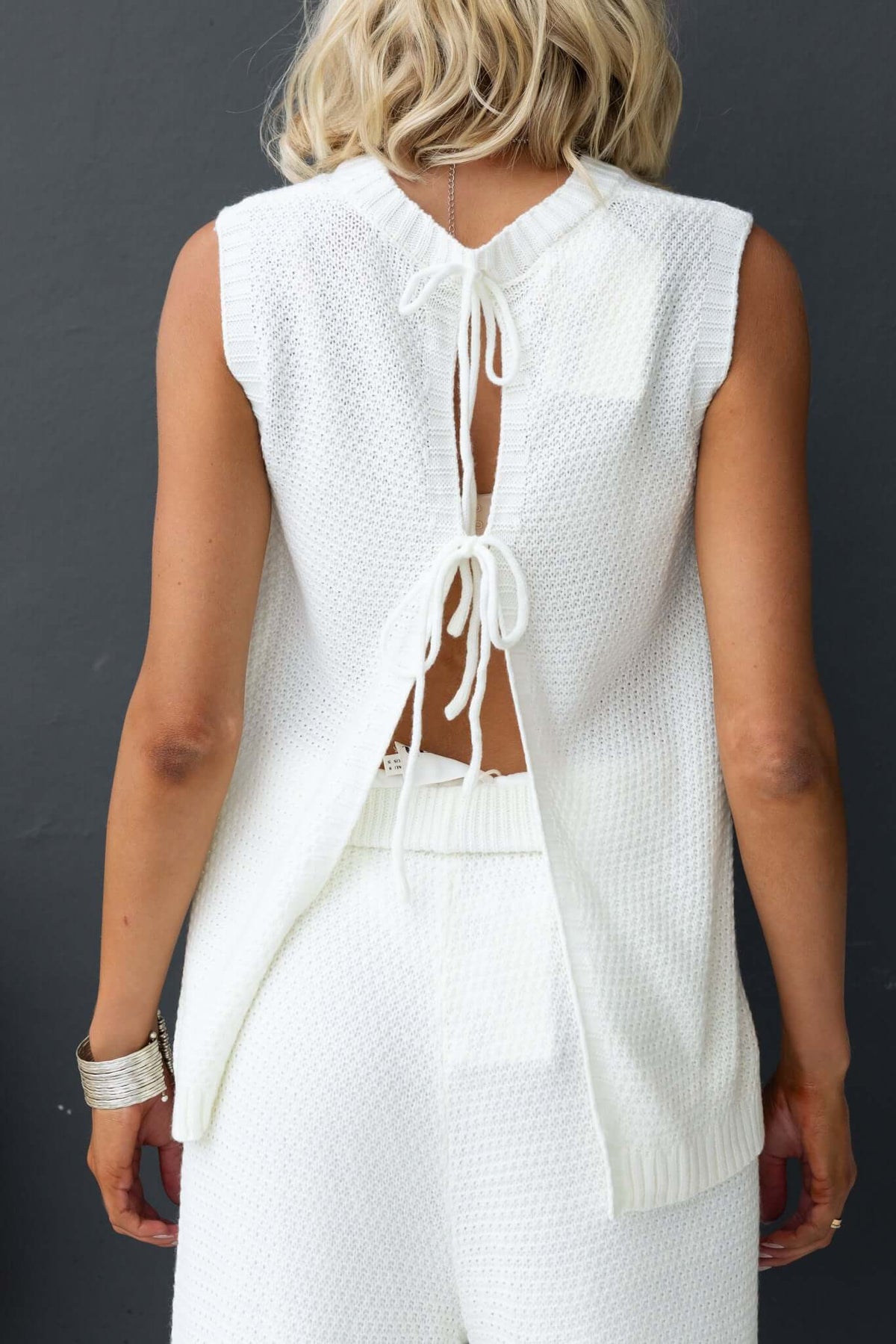 Aera Top featuring a high neckline and open back tie details, made from stretchy knit material.