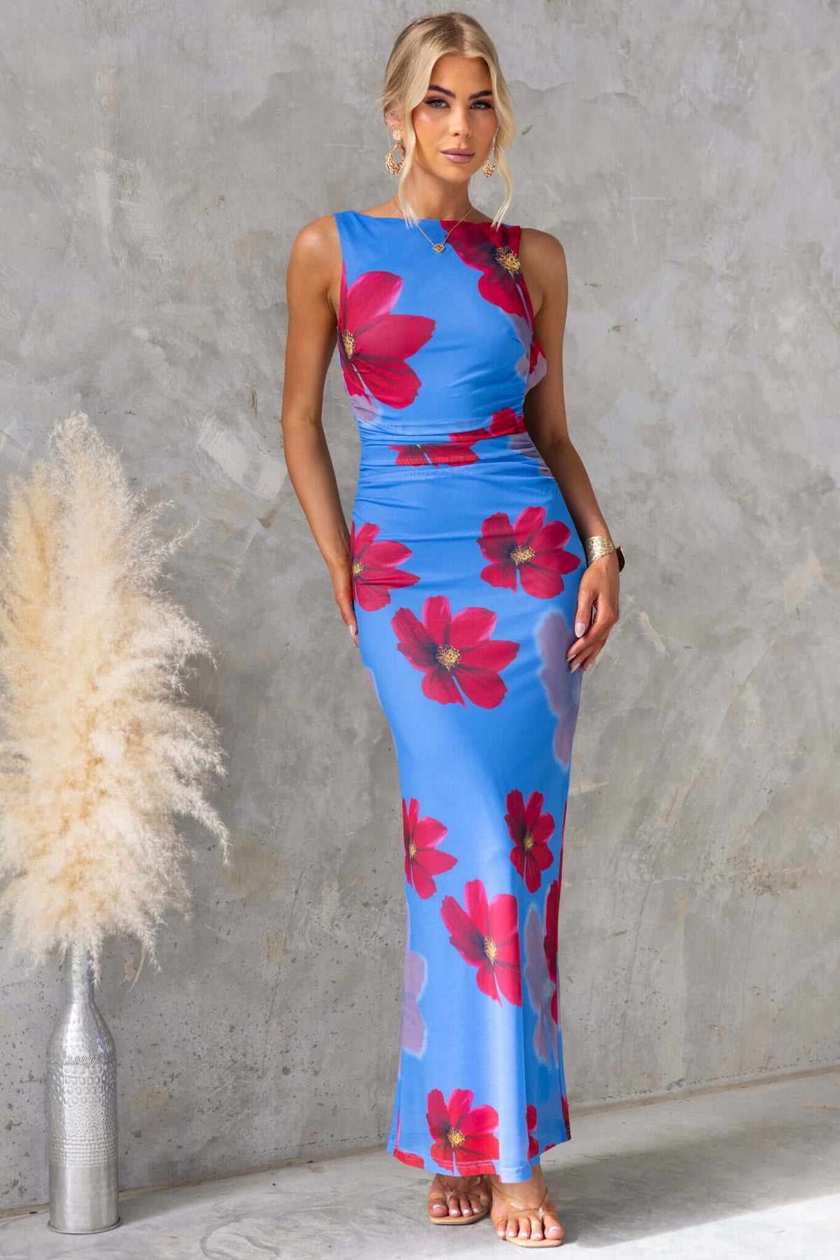 Model wearing Alvara Maxi Dress in blue with floral print, featuring adjustable straps and a high neckline.