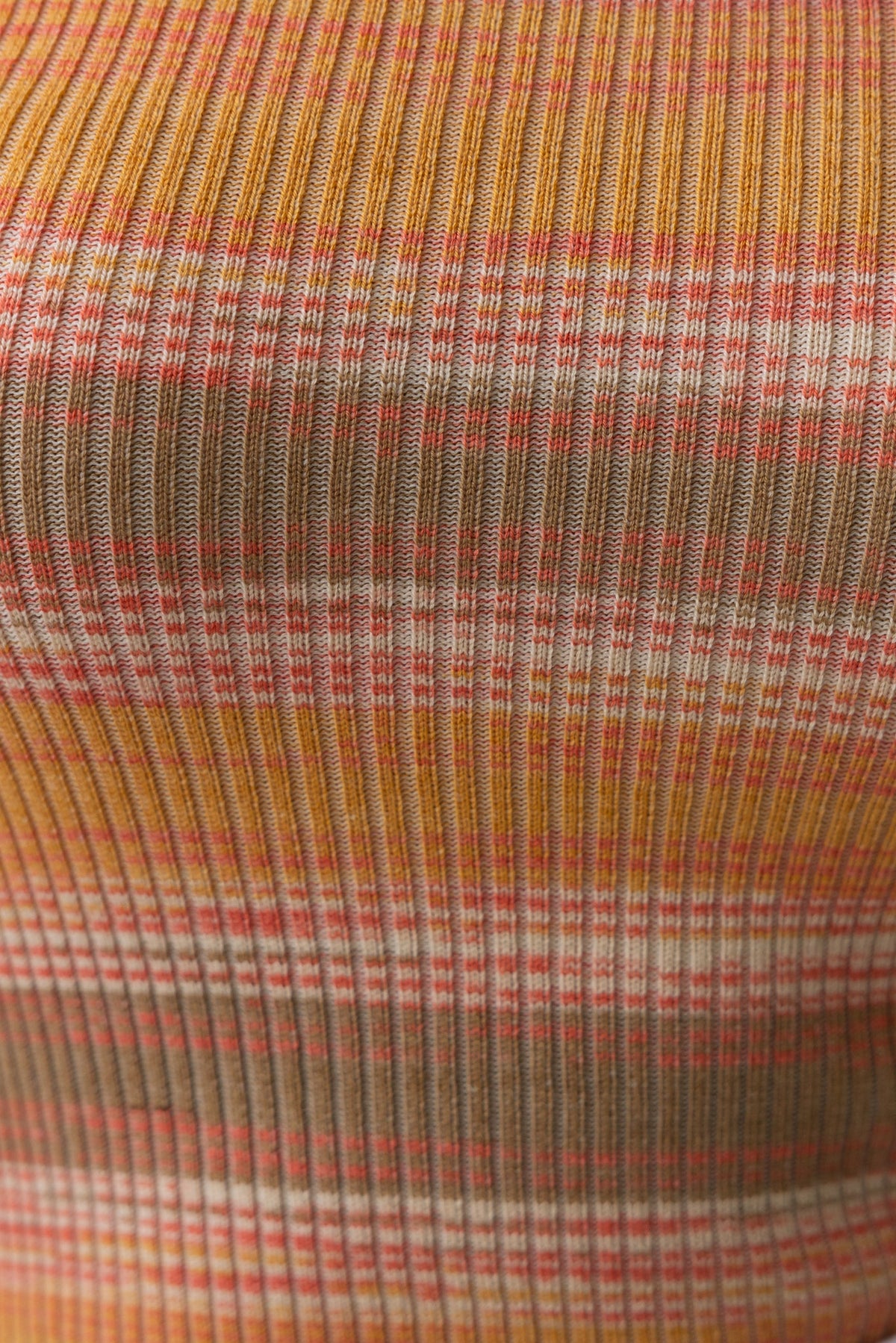 Close-up of ribbed knit fabric in warm colors featuring stripes in orange, beige, and pink, perfect for the Citrine Top.
