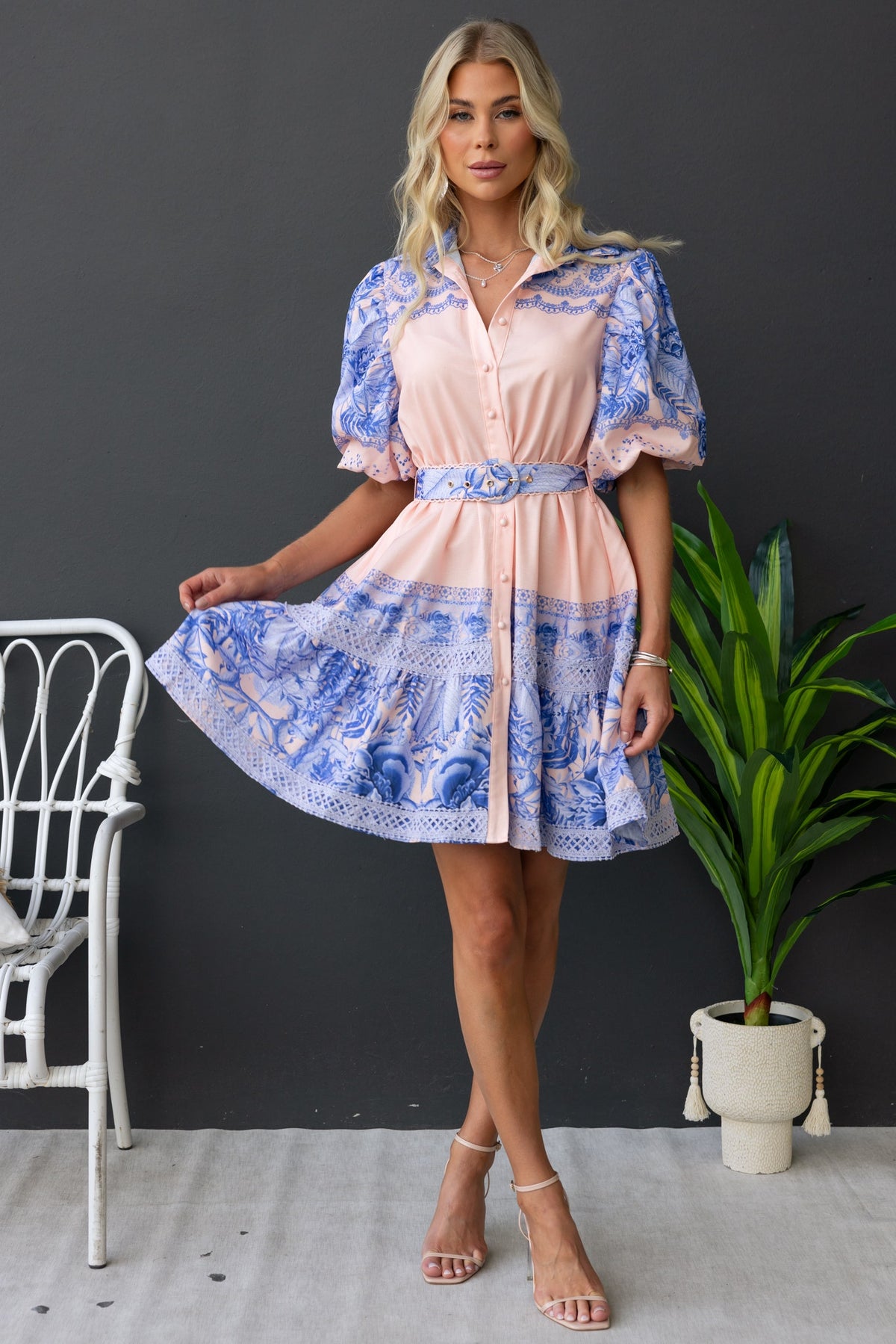 Model wearing the Cillie Dress, a floral print collar dress with puff sleeves and a removable belt.