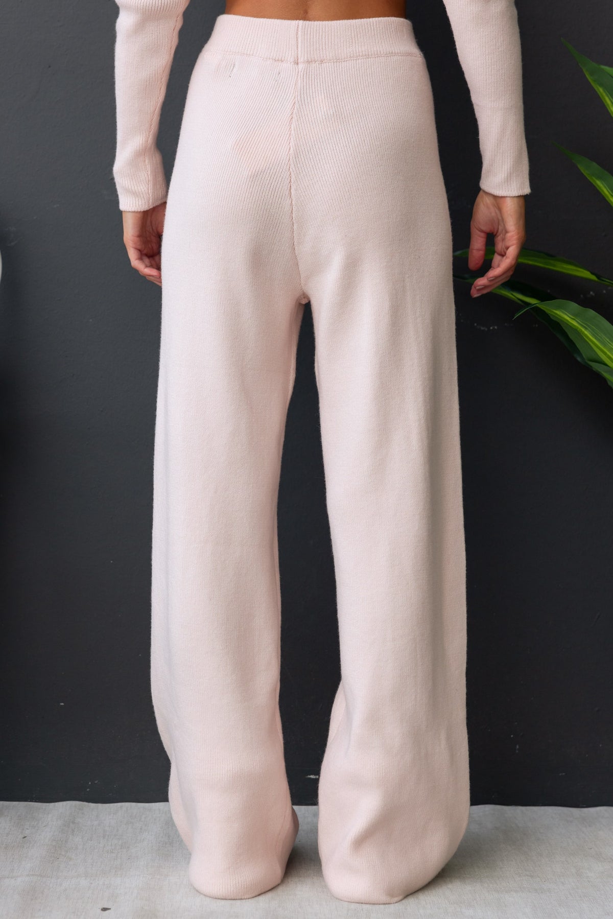 Back view of Darana Pants in soft pink, featuring wide legs and elastic waistband, made from stretchy knit material.