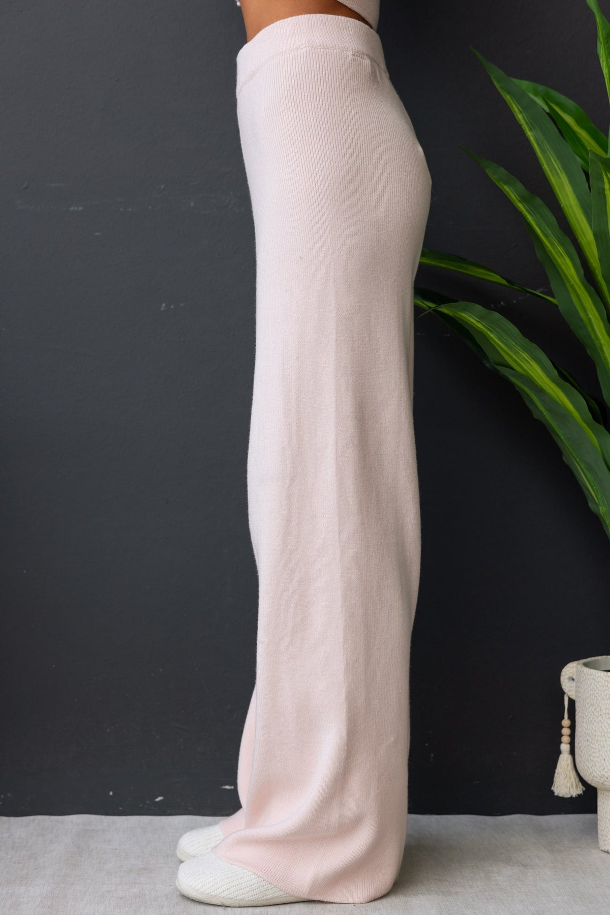 Side view of Darana Pants in soft pink, featuring a mid-high waist and elastic waistband, made from stretchy knit material.