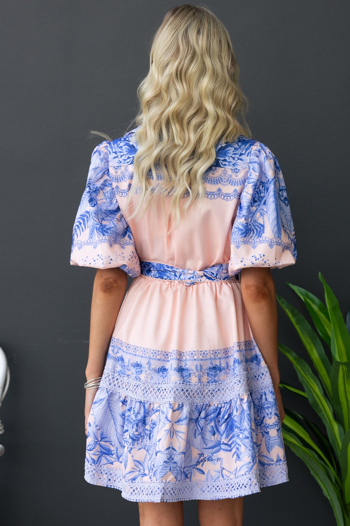 Back view of Cillie Dress featuring floral print, puff sleeves, and removable belt in pink and blue tones.