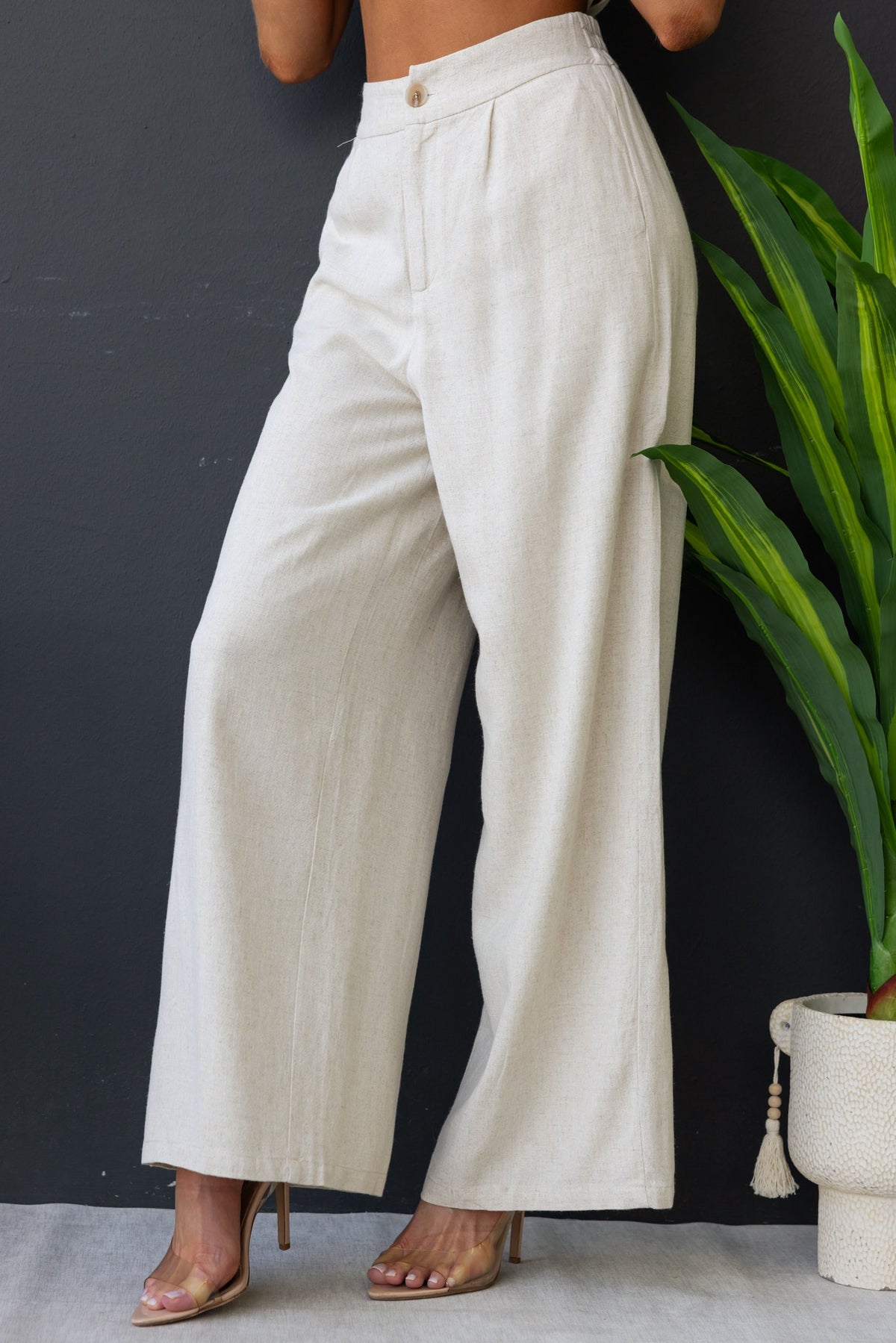 Bexley Pants featuring mid-high waist fit, linen fabric, and pockets, styled with a plant backdrop.
