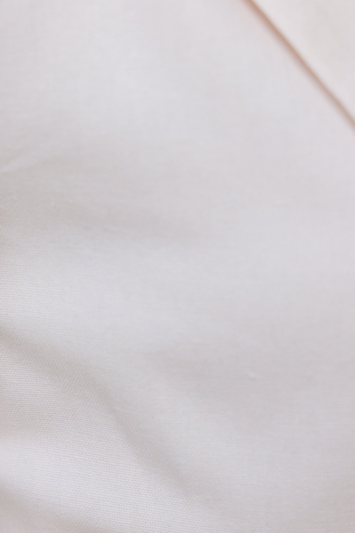 Close-up of the fabric texture in light beige color, showcasing a soft and smooth surface for the Merci Blazer.