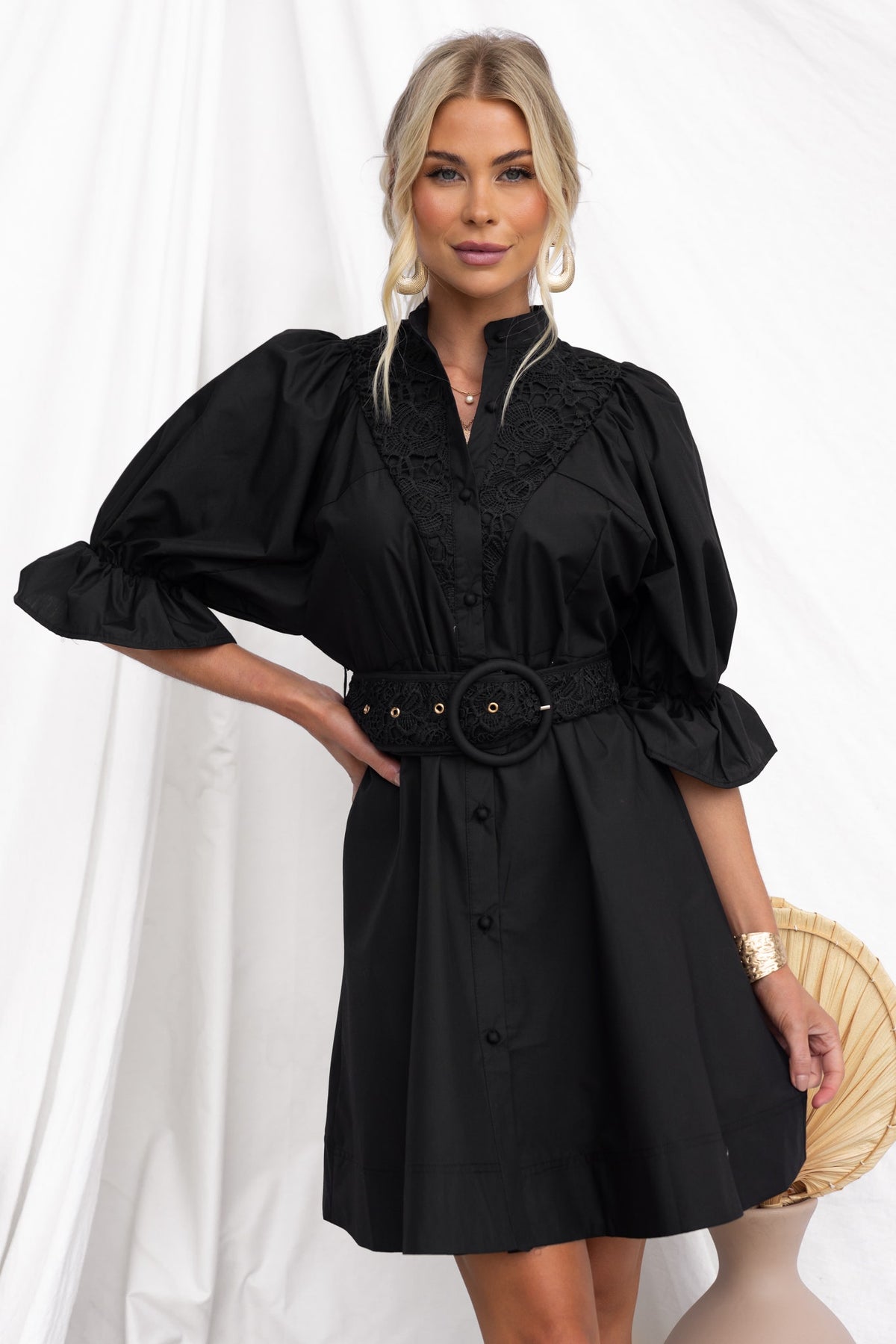 High-neck black Cortez dress with button-up front, lace detailing, and removable belt, styled for a chic look.
