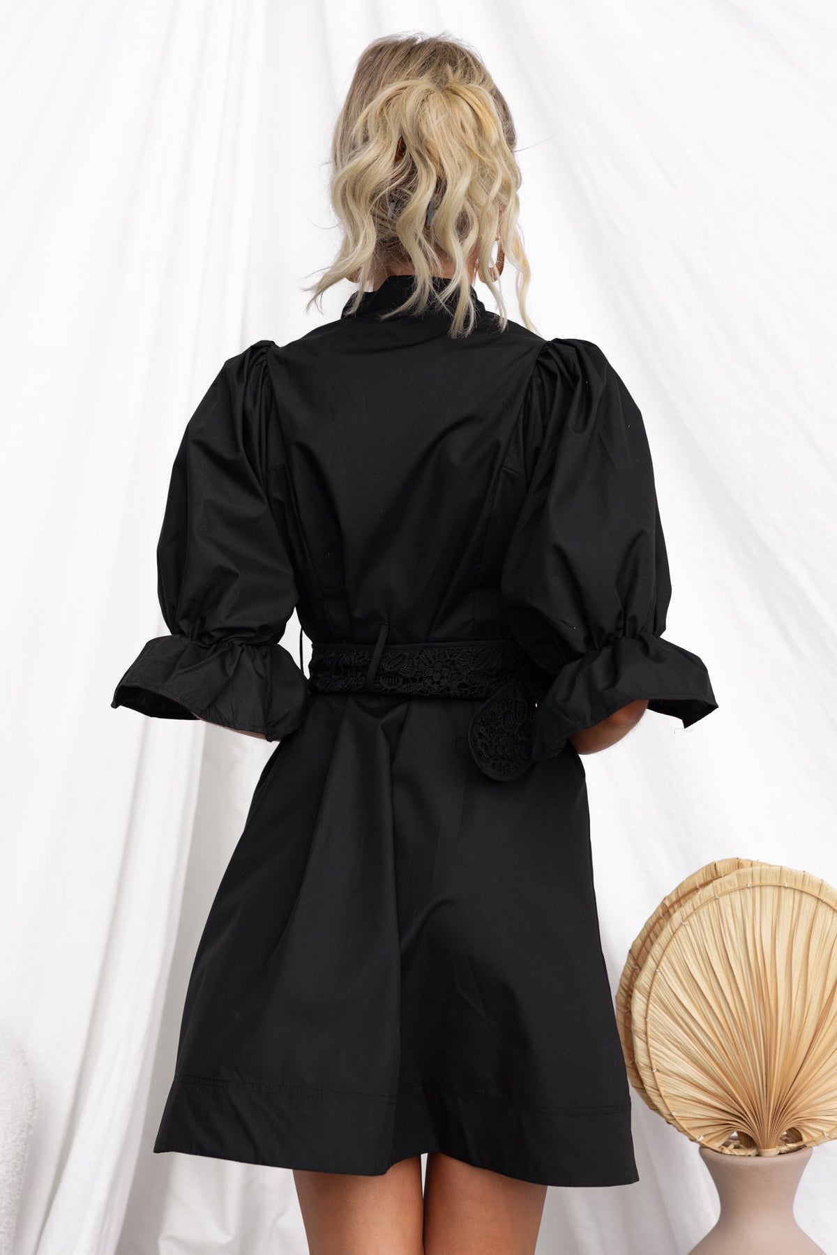Back view of the Cortez Dress showcasing its black fabric, puff sleeves, and removable belt.