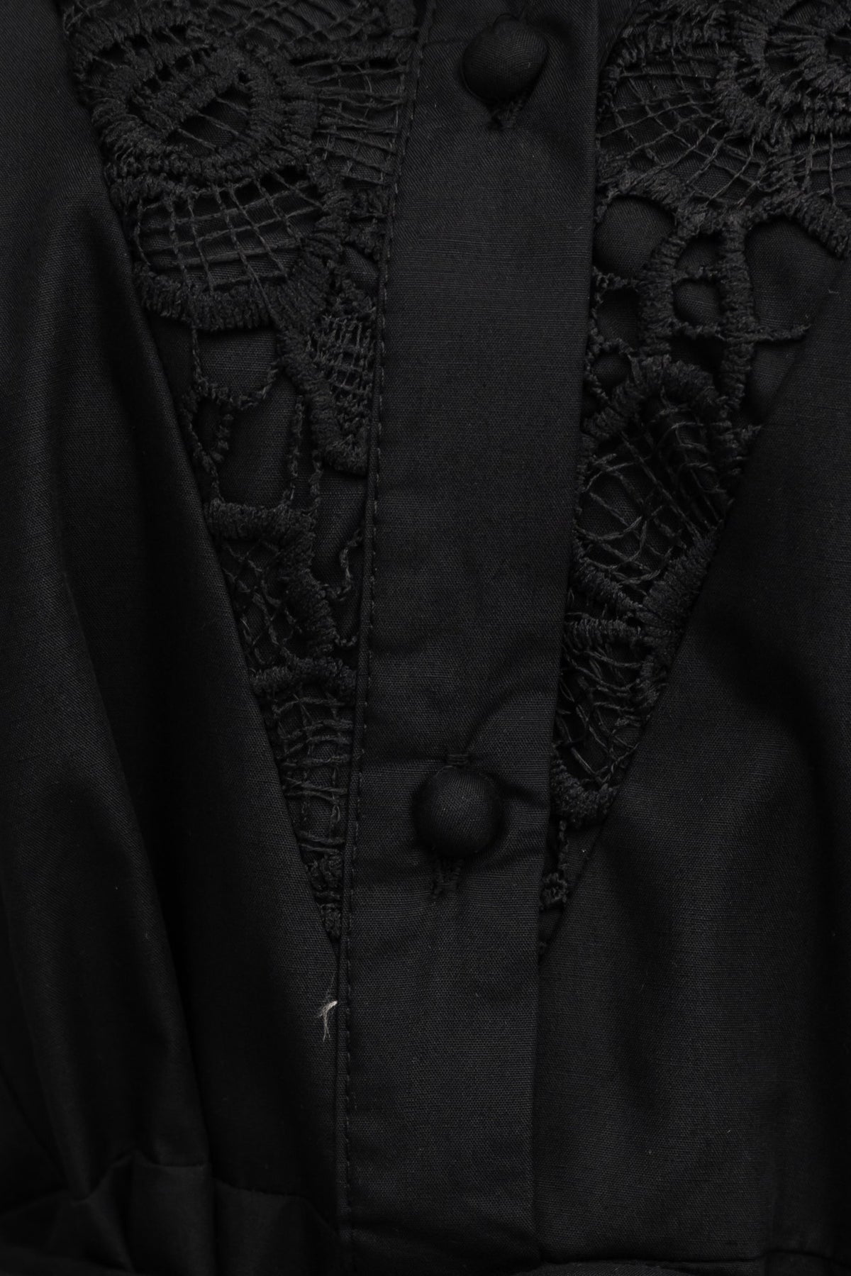 Close-up of black Cortez Dress featuring lace detailing and button-up front.