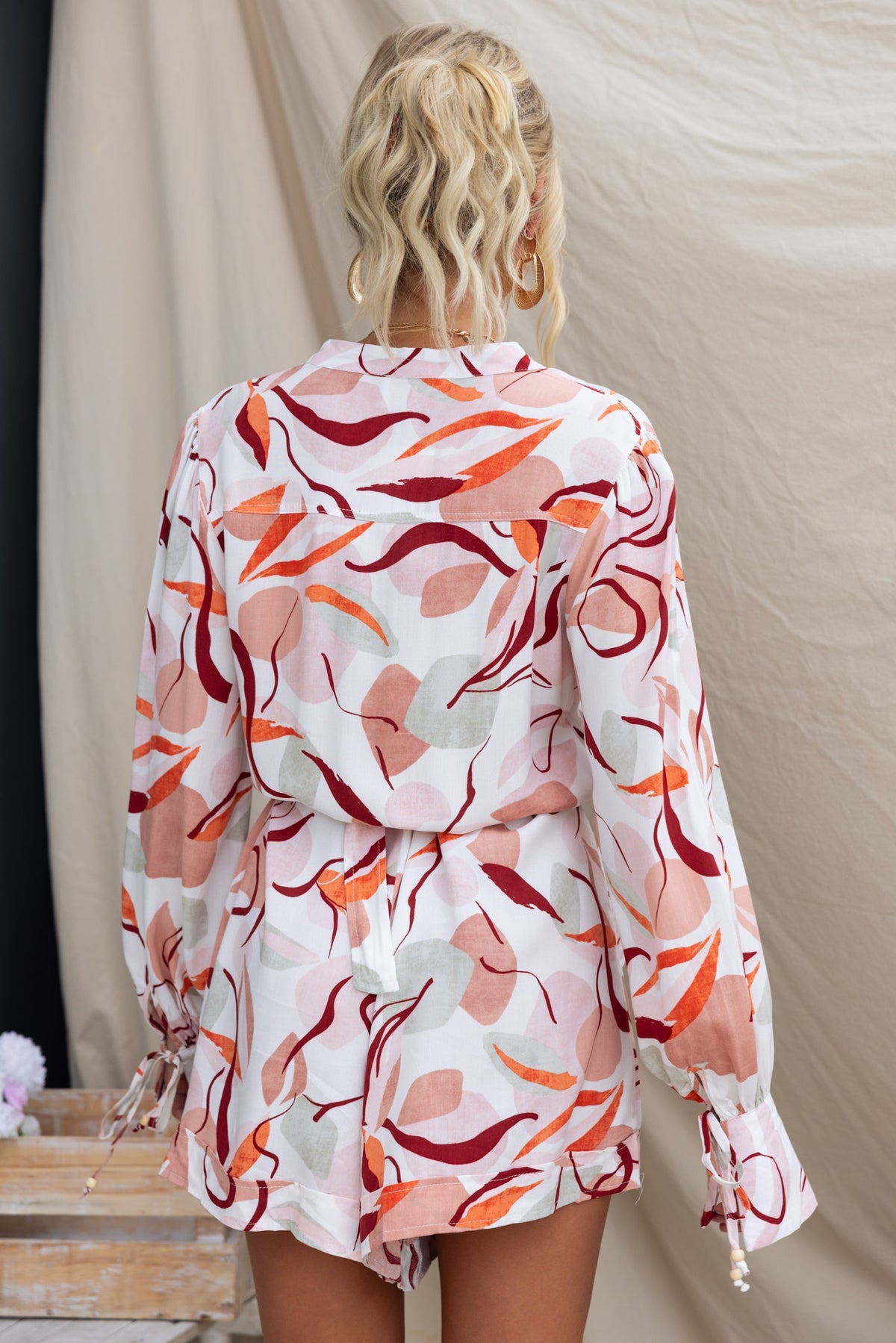 Back view of Alfred Playsuit featuring colorful abstract print, long sleeves, and removable belt.