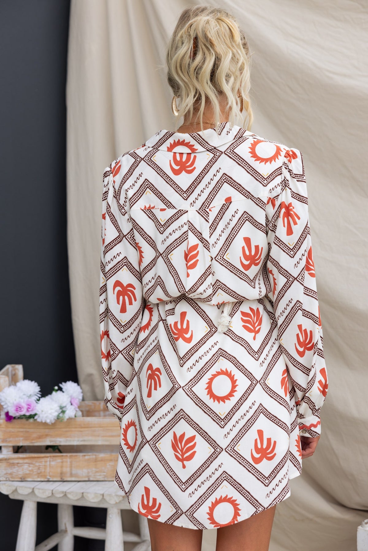 Back view of a model wearing the Better Not Dress with geometric patterns in earthy tones.