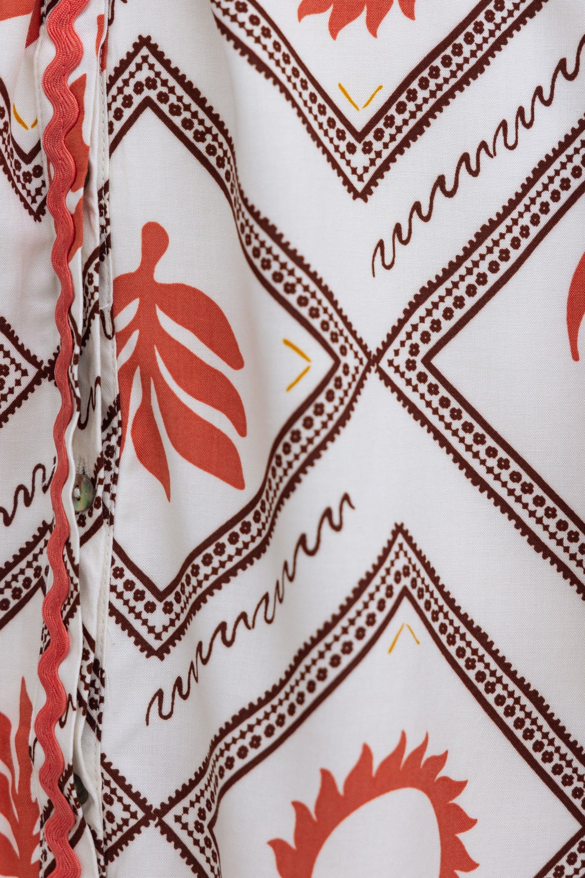 Close-up of a patterned fabric featuring red leaf designs on a white background, showcasing the unique textile style.