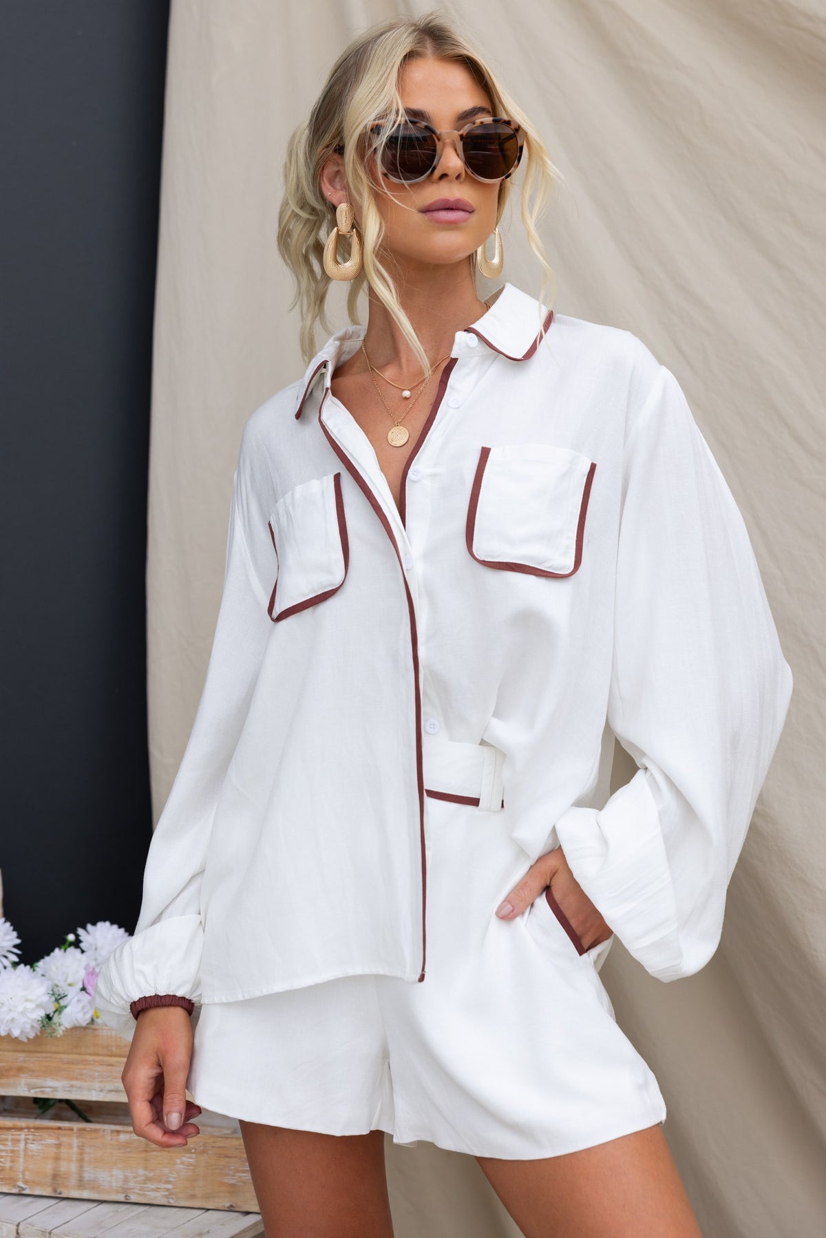 Model wearing a stylish Ronnie Shirt with pockets and button-up front, paired with shorts and sunglasses.